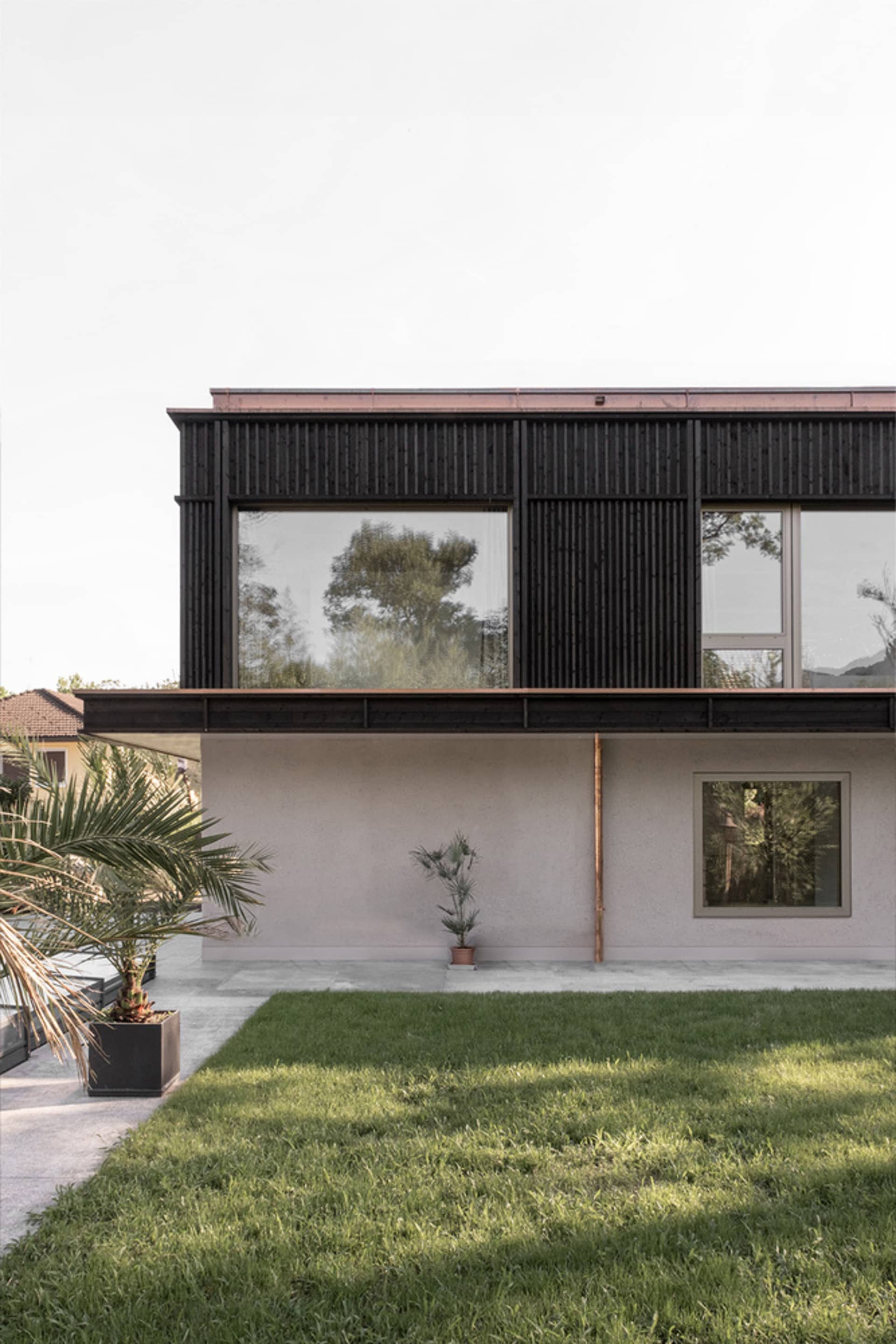 A modern house with a concrete exterior featuring large windows and a minimalist design.