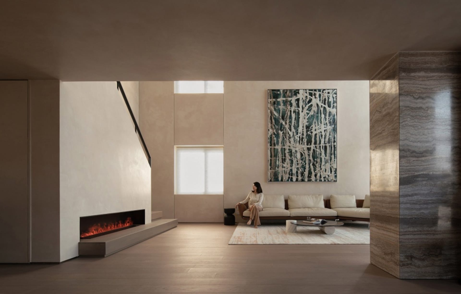 A modern minimalist living room featuring concrete and marble materials, with a woman sitting on a sofa.