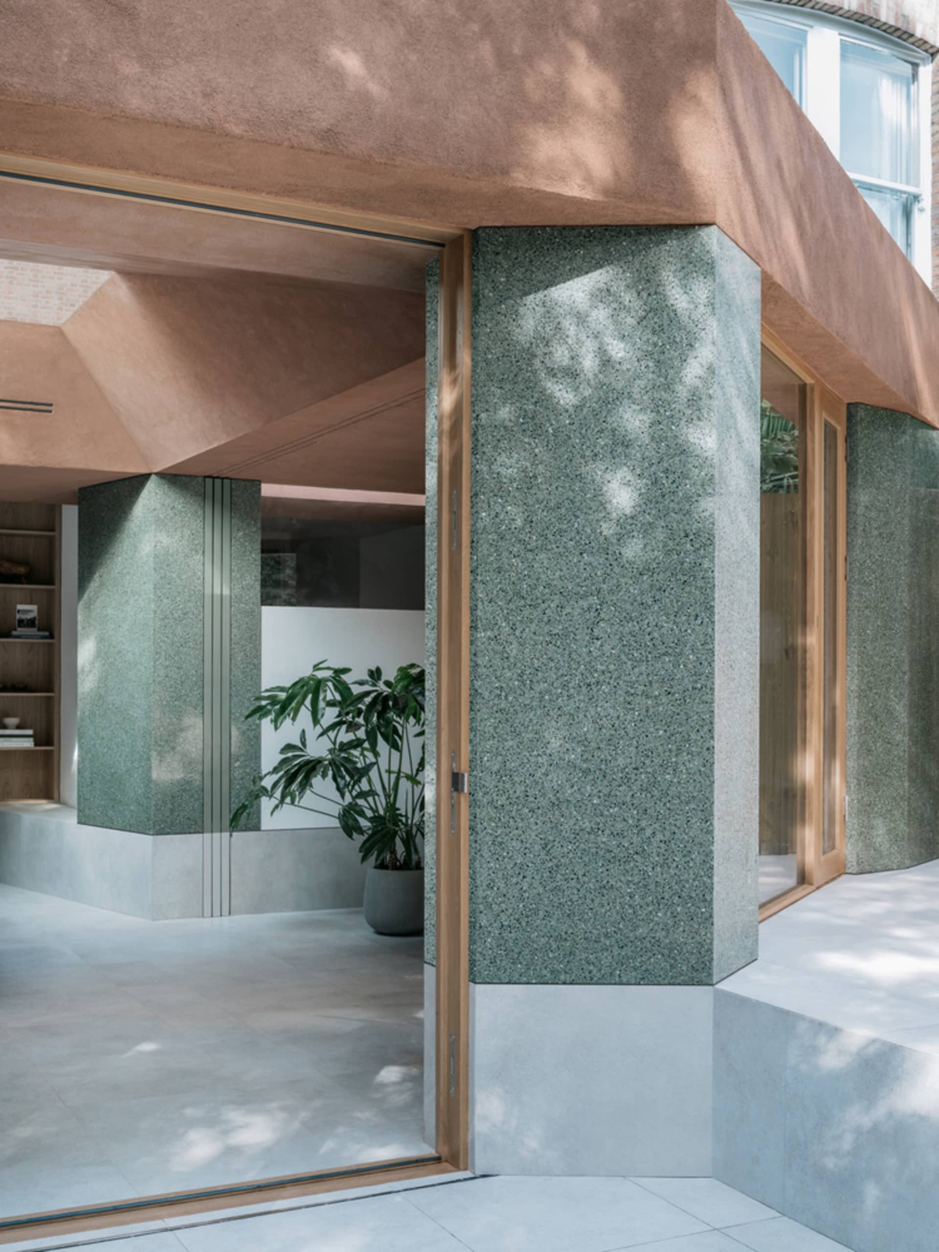 Modern interior design featuring a grand atrium entrance with granite columns and concrete flooring.