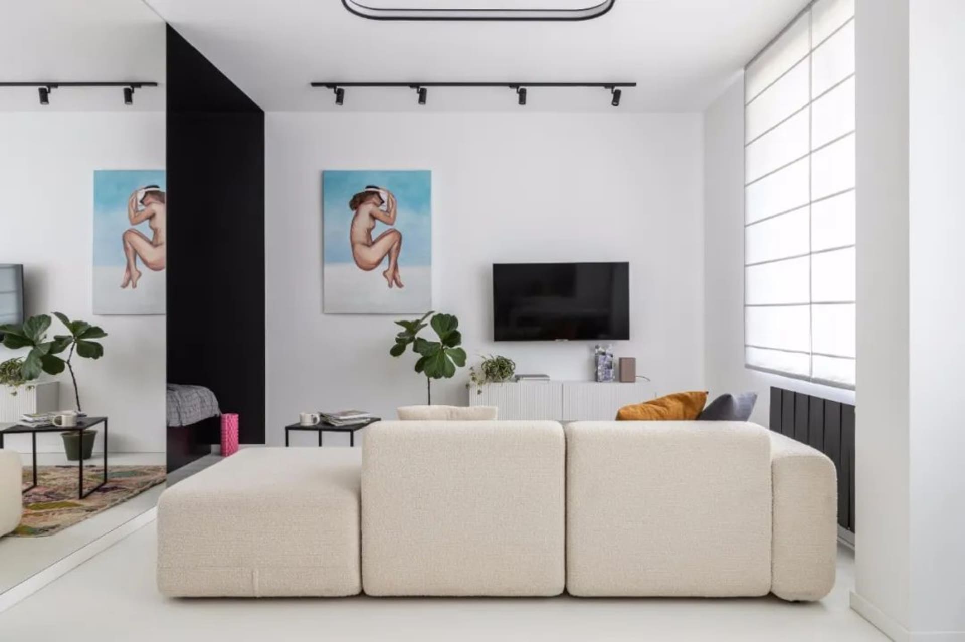 Modern living room featuring a minimalist white and cream color palette, a comfortable beige sectional sofa, and a flat-scree