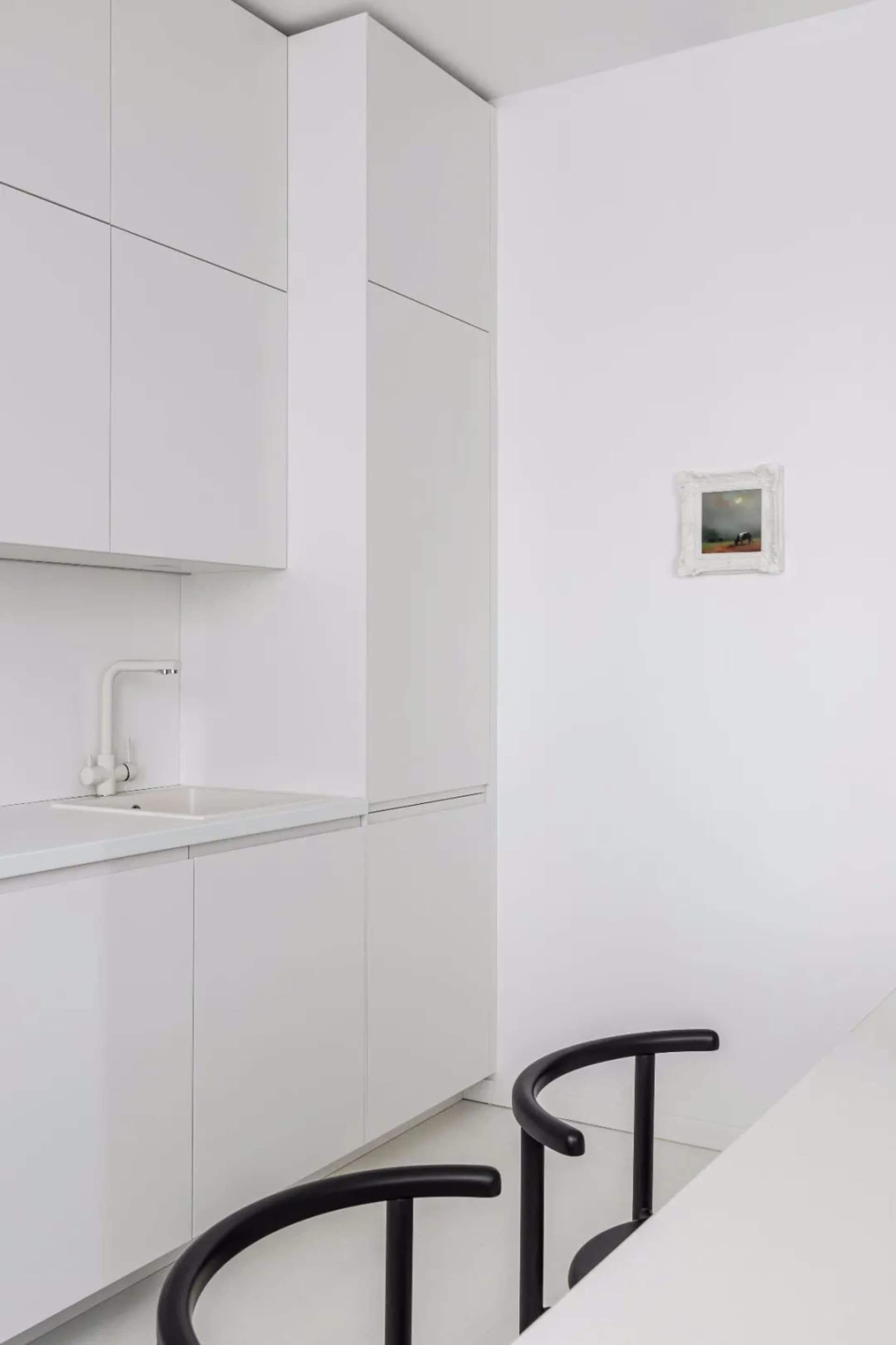 Modern minimalist kitchen featuring sleek white cabinets and minimalist design.