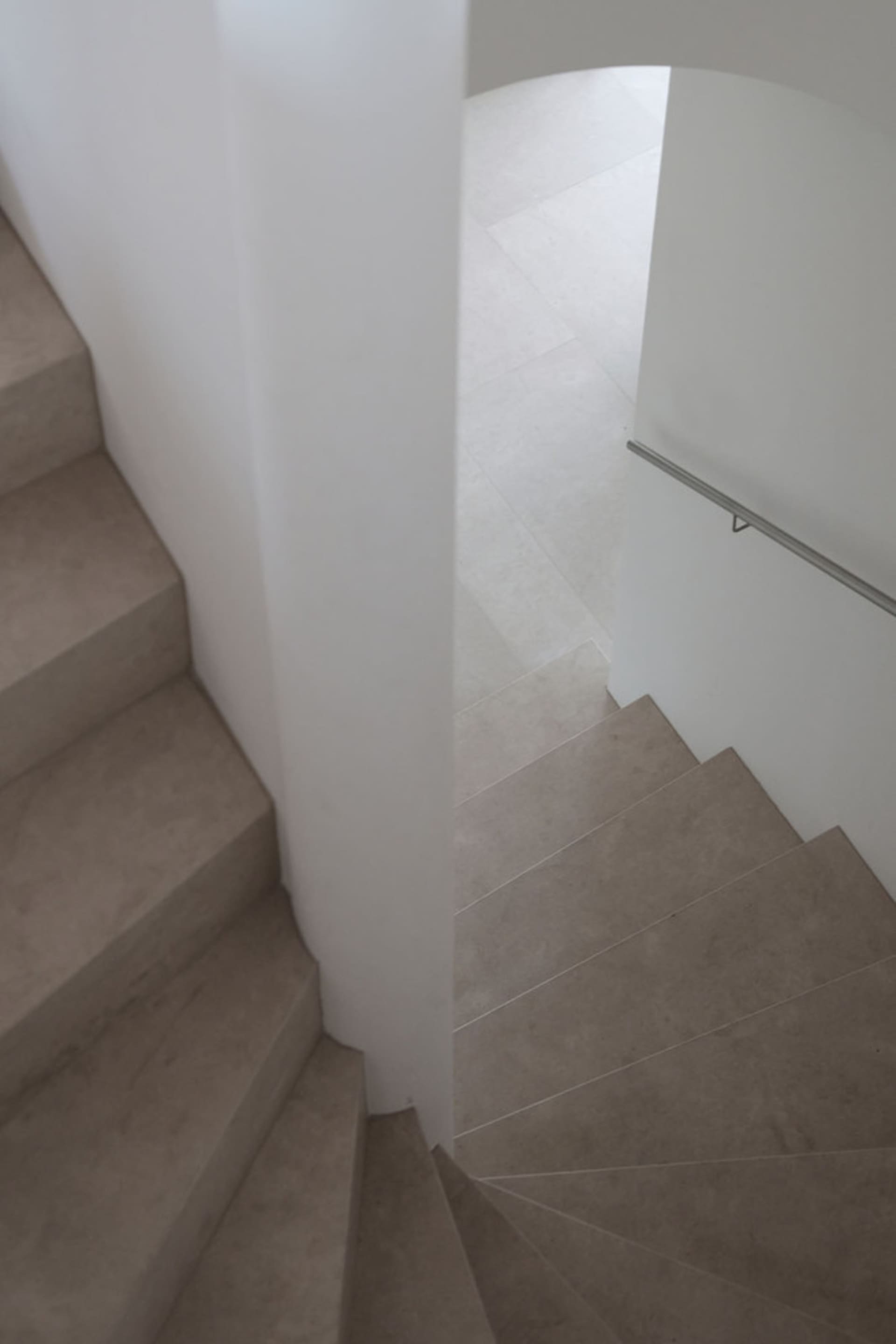 A modern staircase with minimalist design features concrete steps and a white wall.