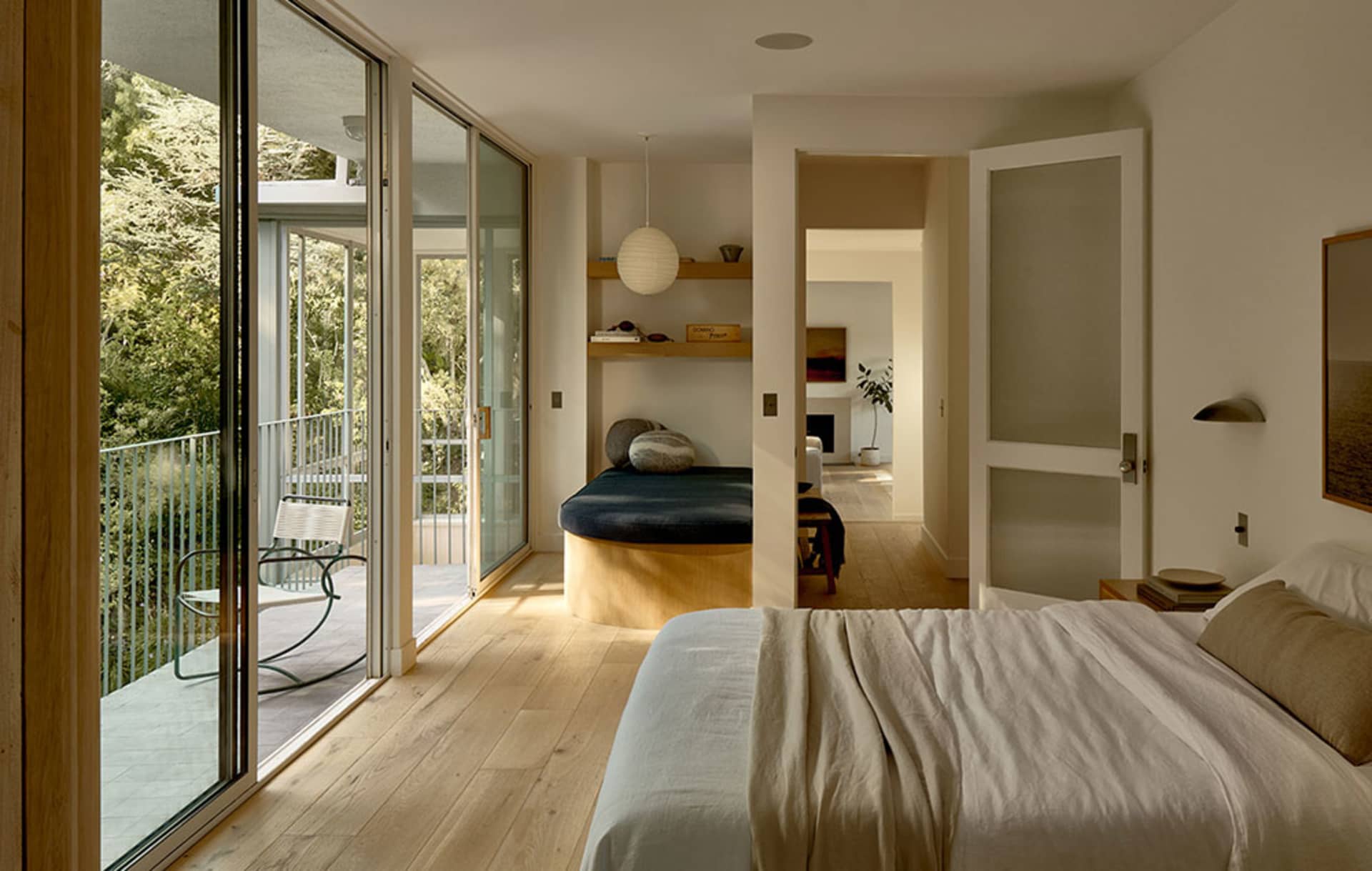 Minimalist bedroom with a white bed and wooden floor.