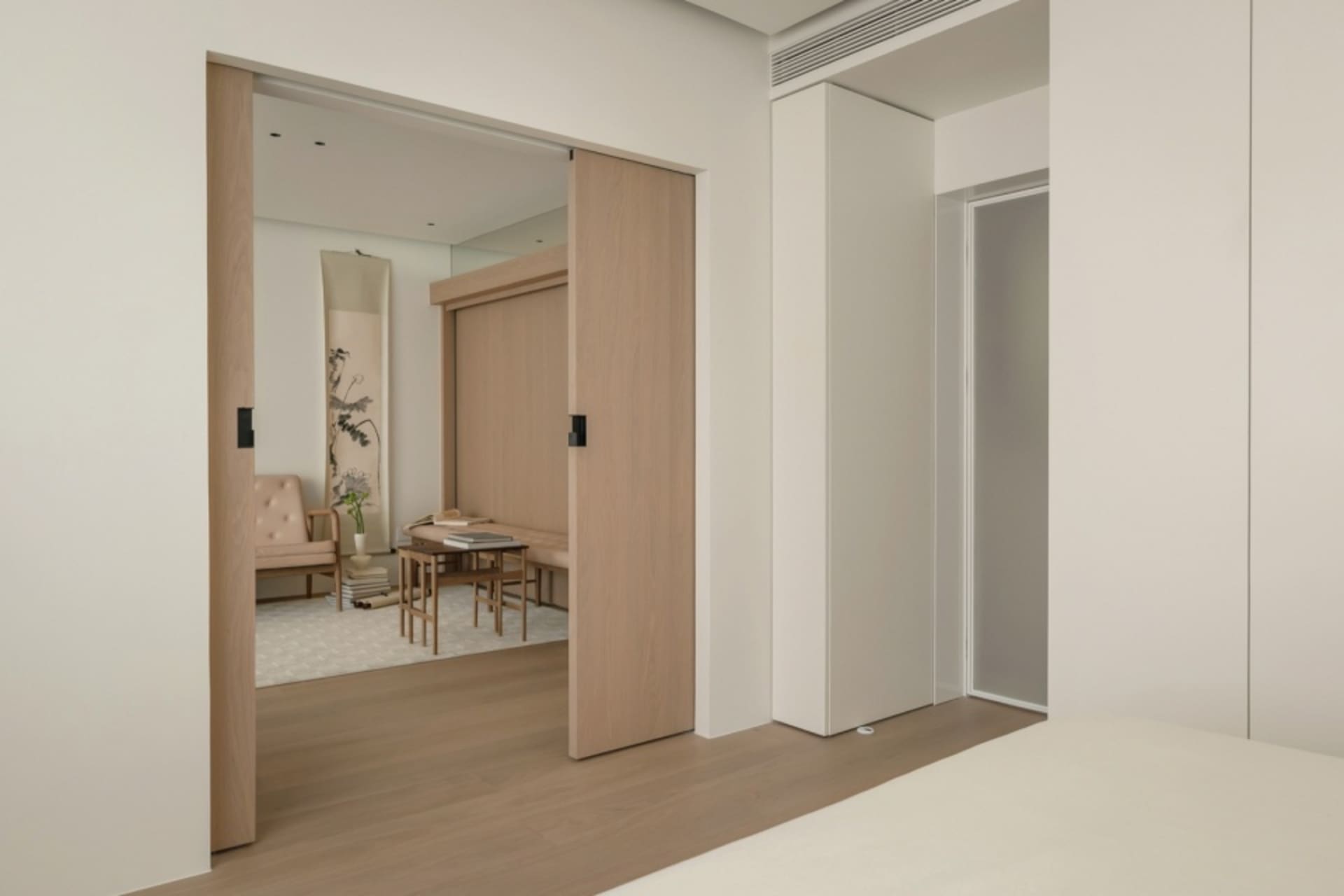 A minimalist bedroom featuring wooden furniture and a sliding door.