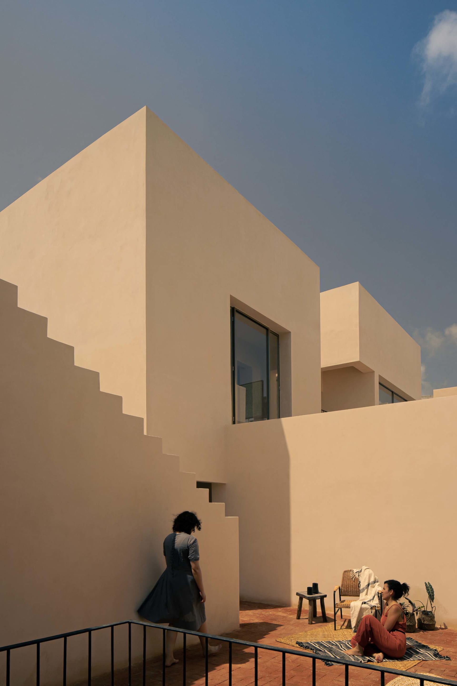 Modern minimalist architecture featuring sandstone buildings with geometric shapes and large windows.
