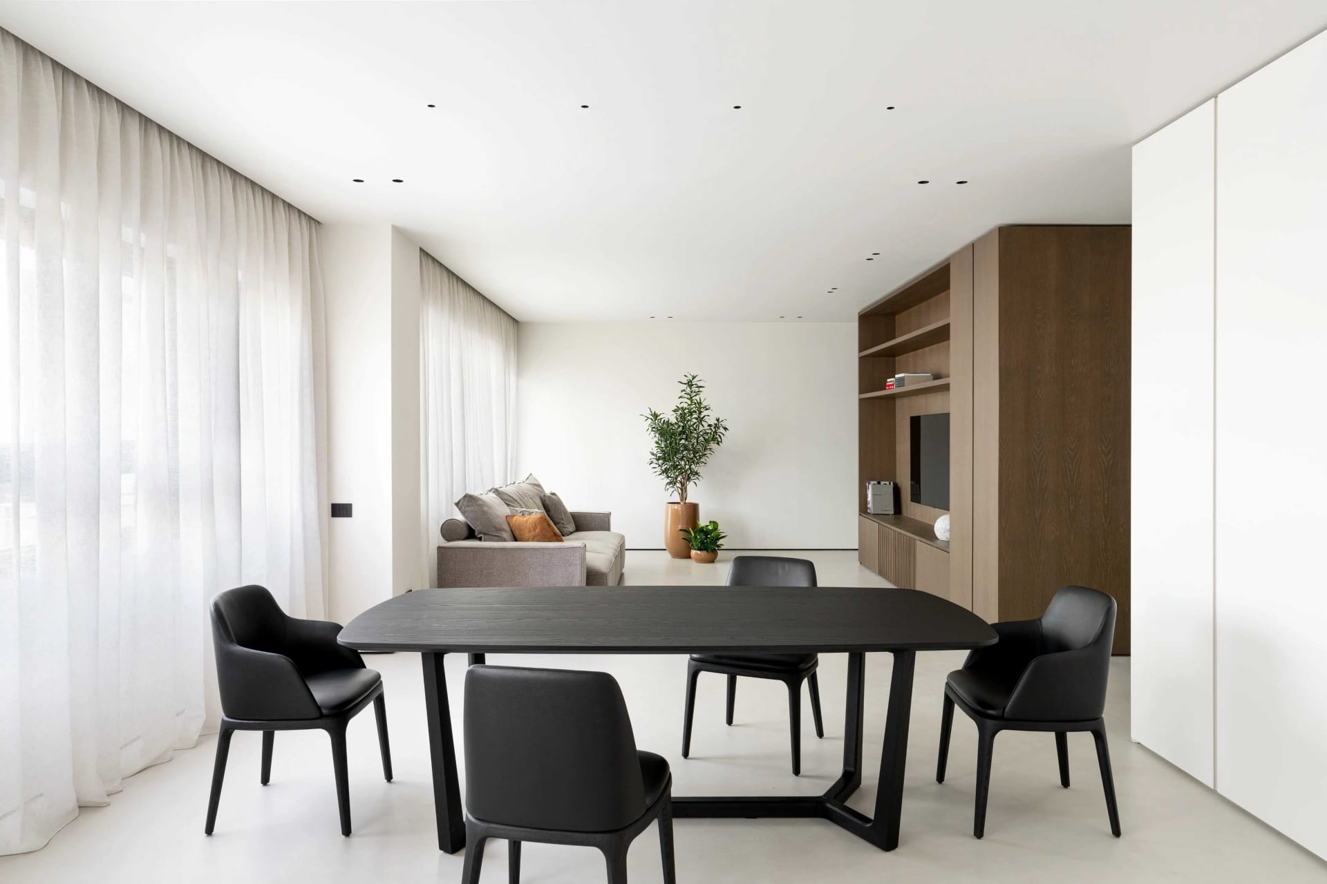 A modern residential dining room featuring contemporary black furniture, white walls, and minimalist decor.
