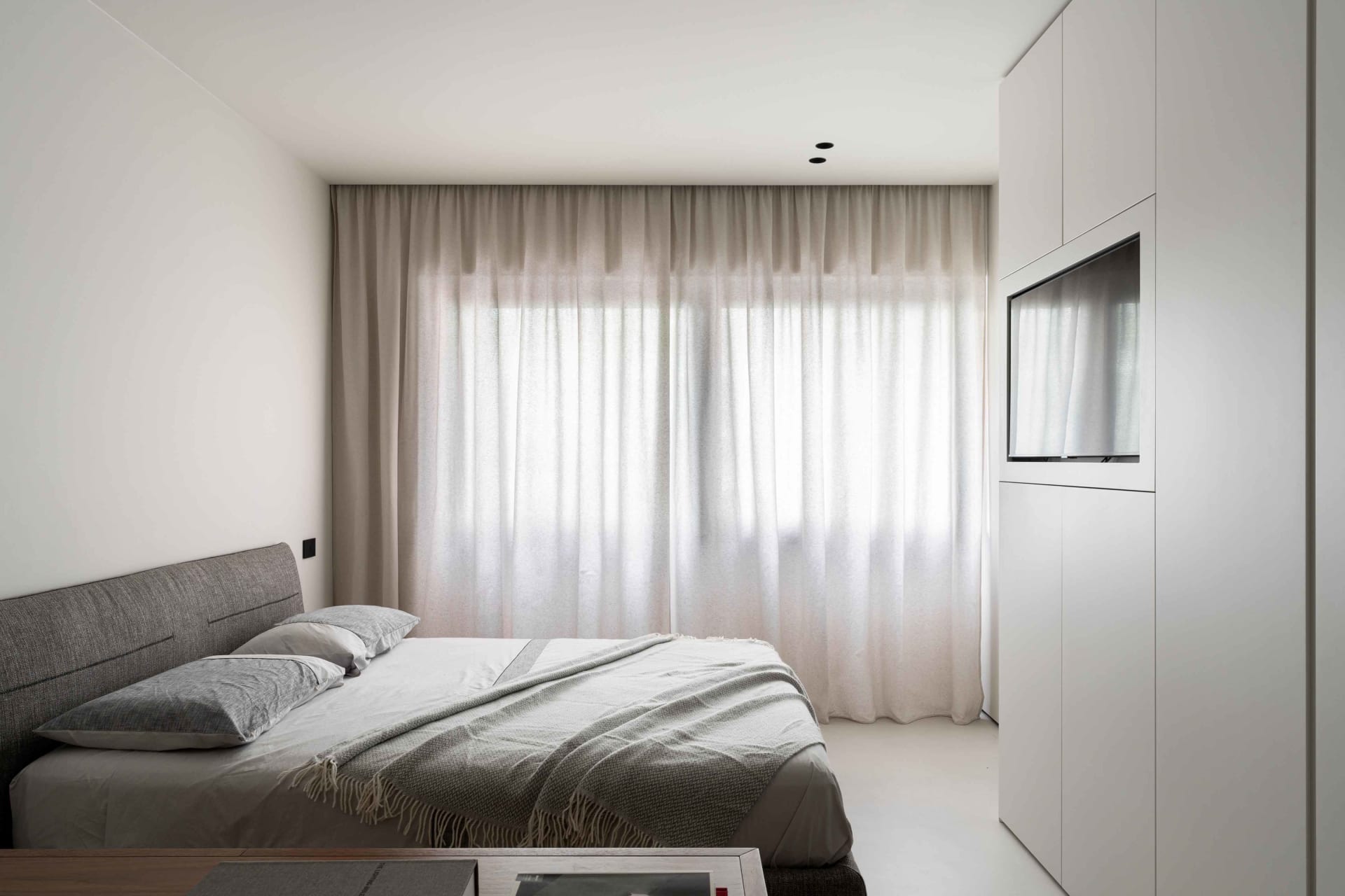 Modern minimalist bedroom featuring soft fabric curtains and sleek glass walls.