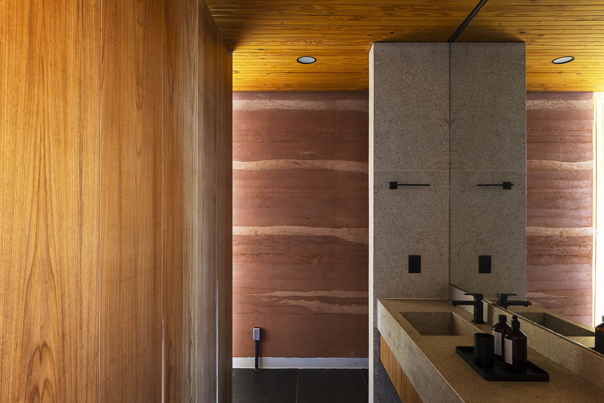 A modern bathroom featuring a concrete floor and walls, with a wooden ceiling and minimalist design.