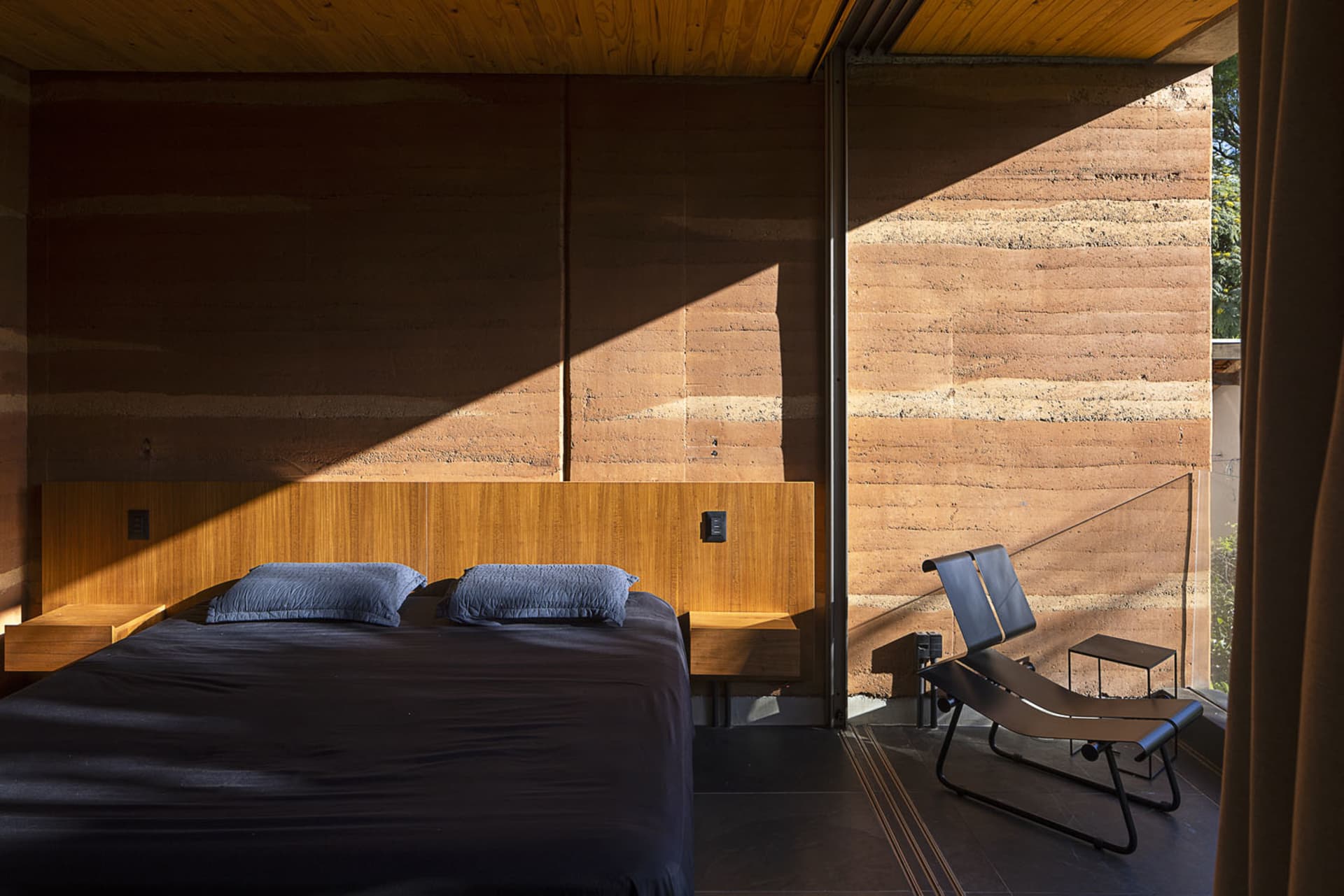 Contemporary bedroom featuring wooden bed frame and concrete wall