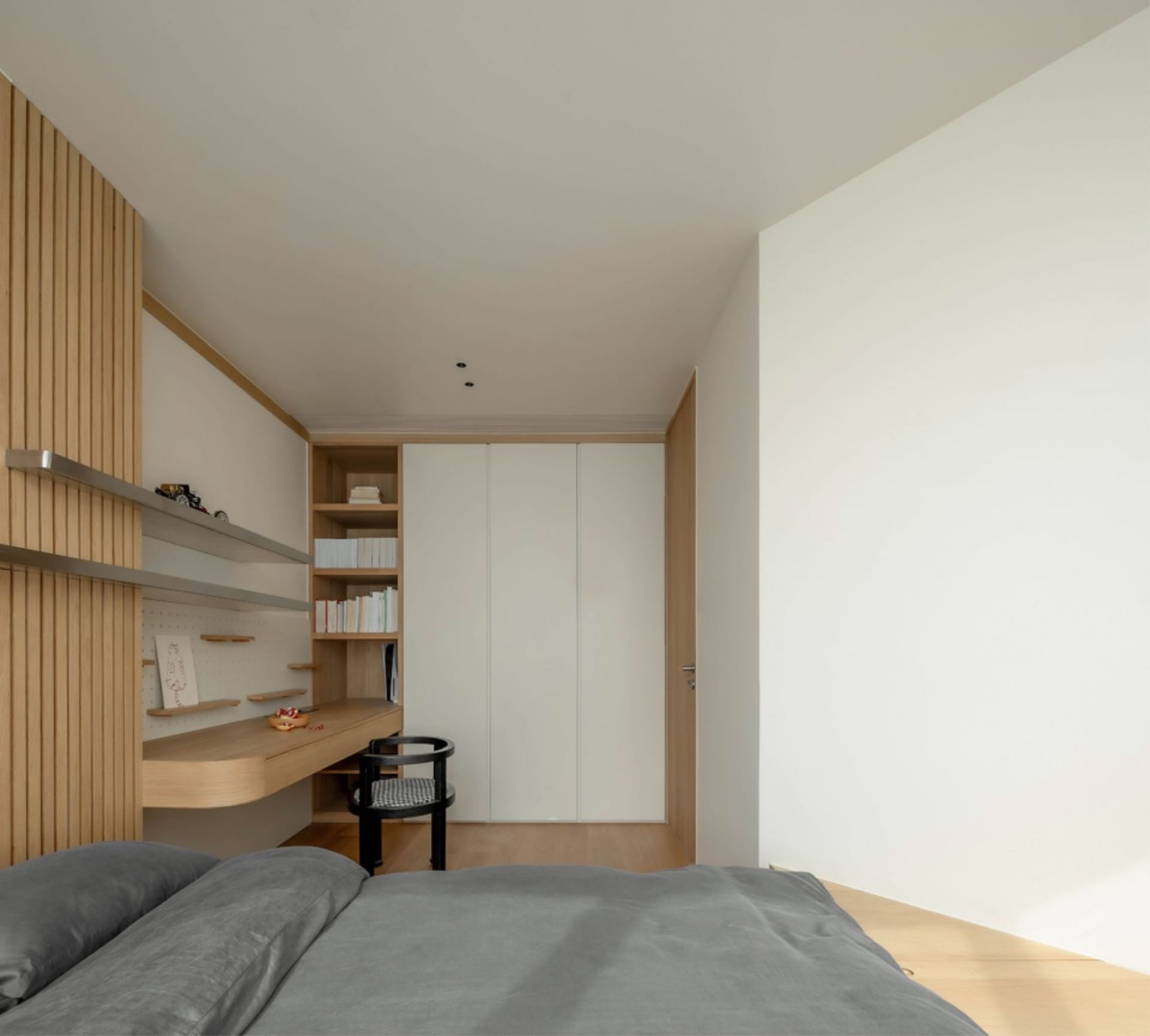 A minimalist bedroom with wooden and metallic elements, including a bed, shelves, and a closet.