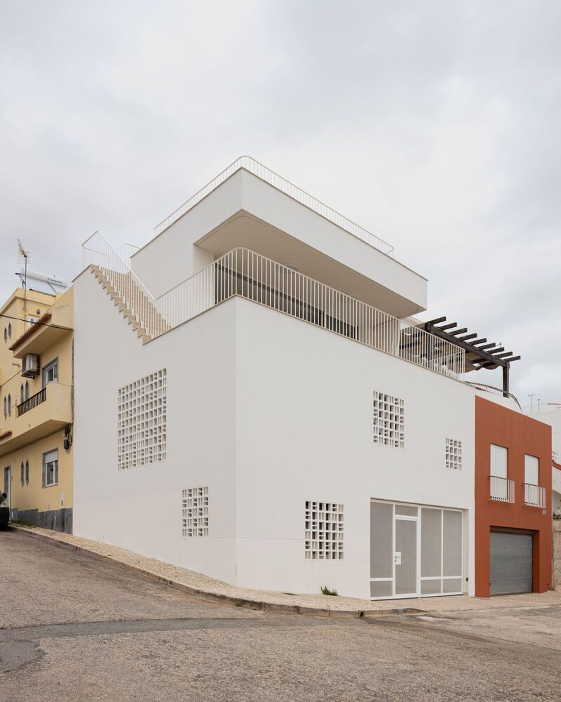 一座現代住宅建築以混凝土與玻璃為特色,設有屋頂樓梯與私人陽台。