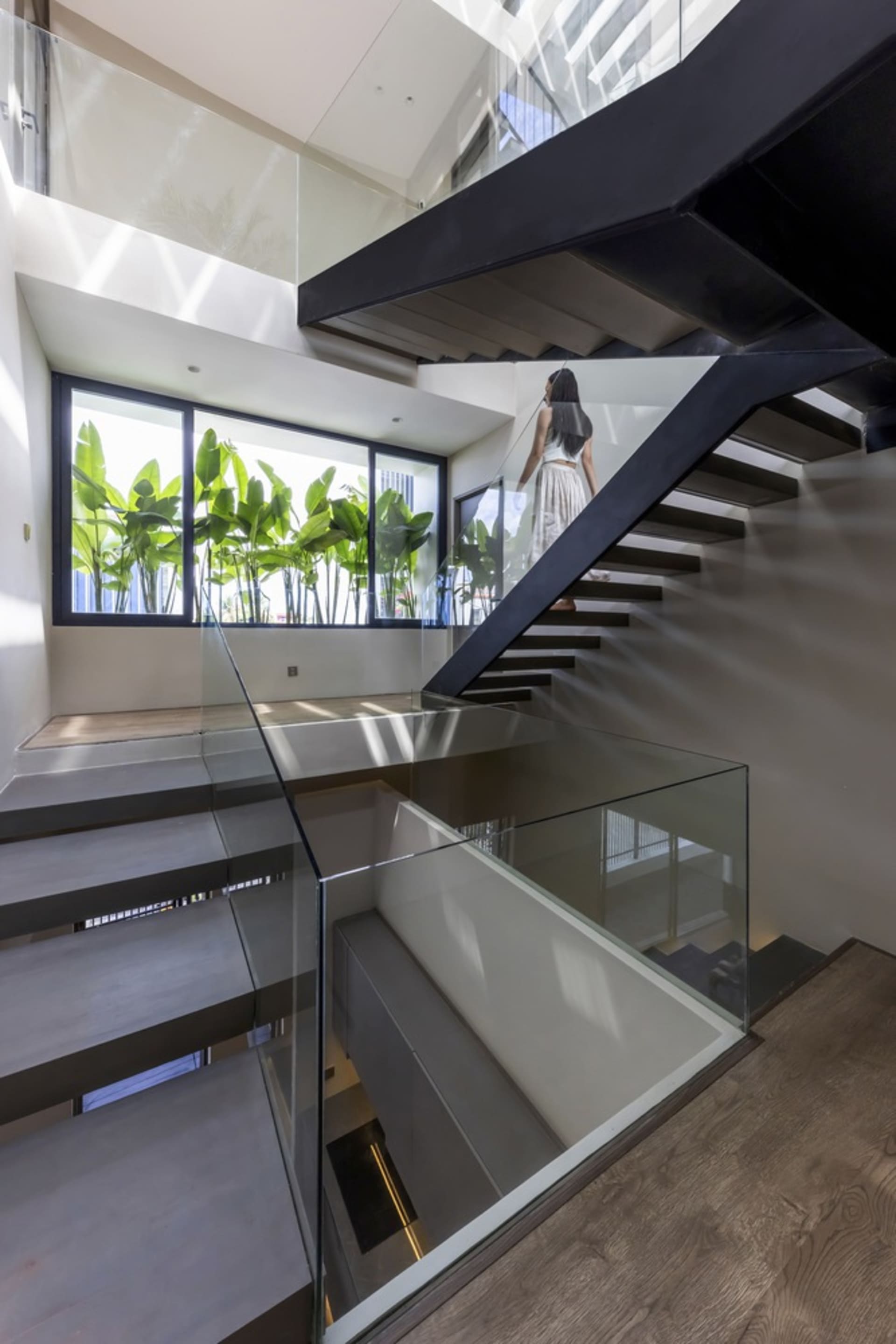 Modern staircase with glass railings and concrete steps, featuring a sleek and contemporary design.