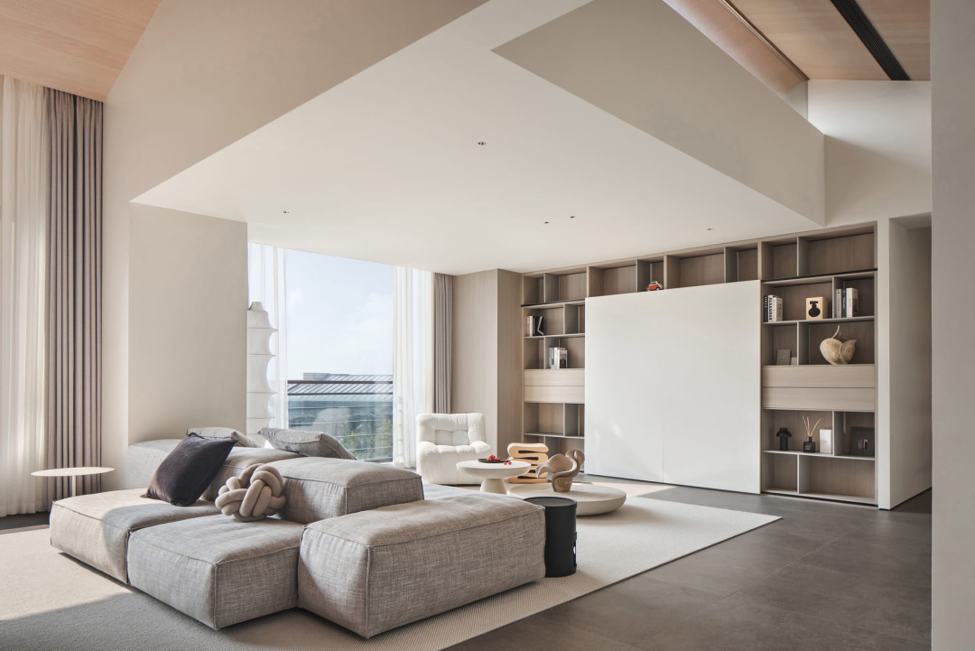 Modern minimalist living room featuring a comfortable sofa, white armchair, and a bookshelf