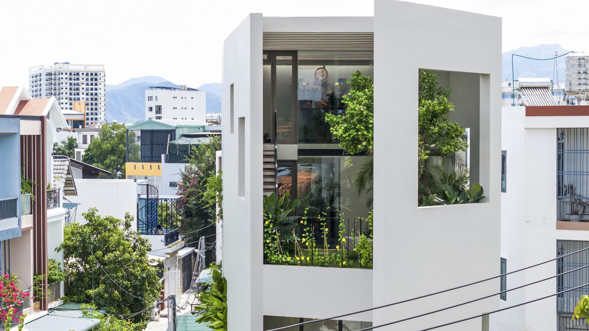 A modern residence featuring glass, concrete, and greenery elements.