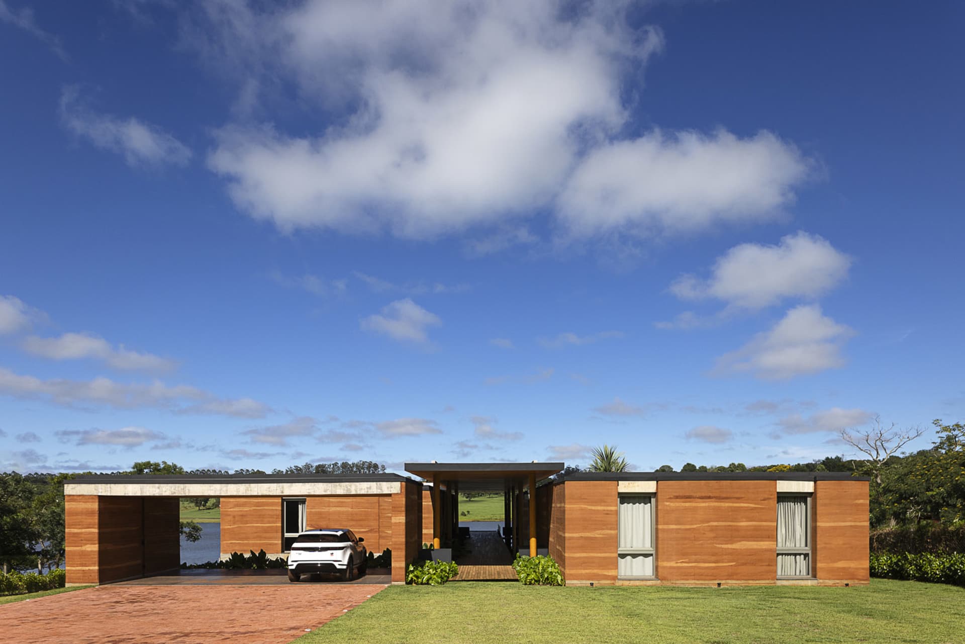 A modern residential building with a wooden exterior and a car parked in the driveway.