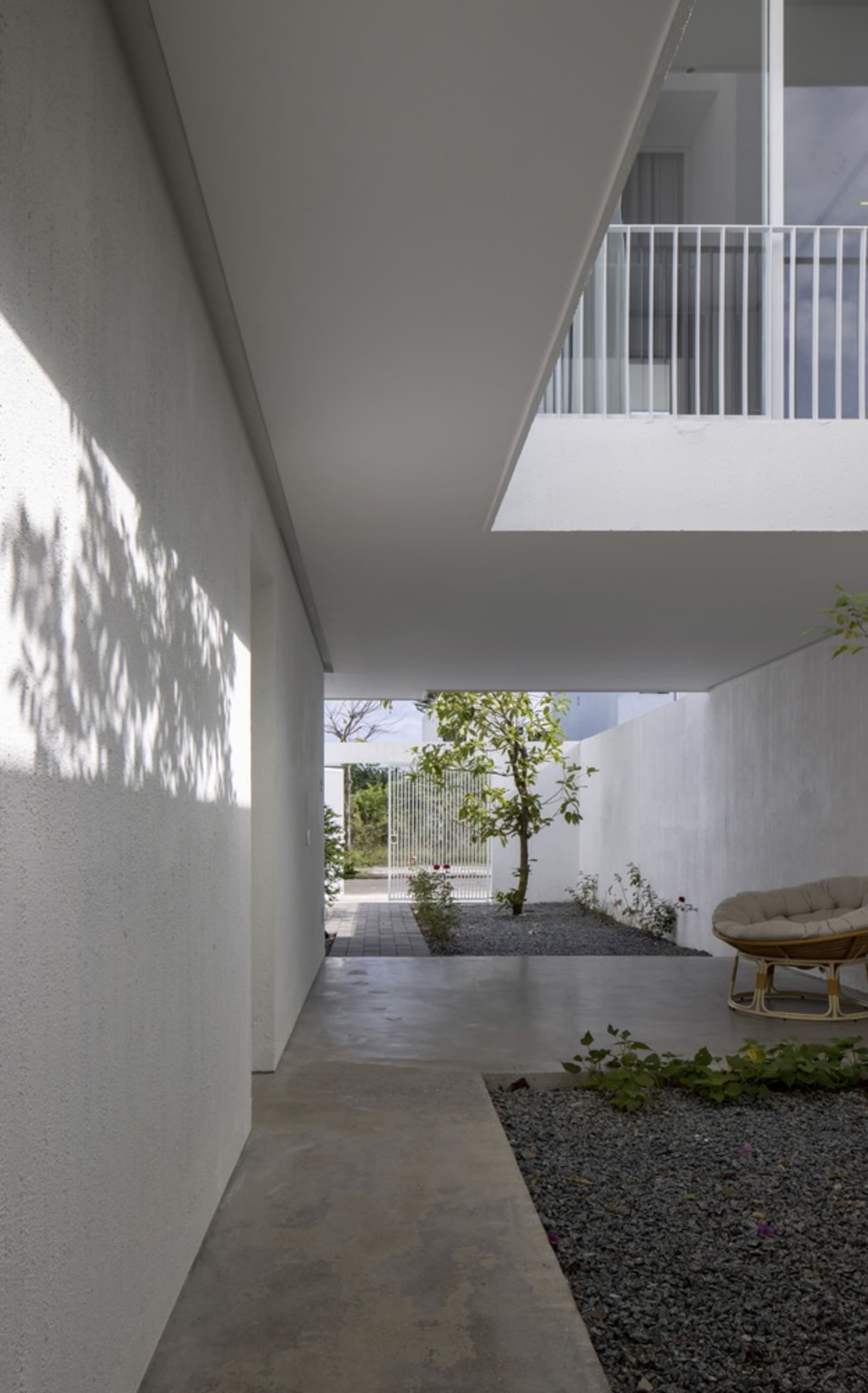 A minimalist house courtyard featuring a concrete patio and gravel garden.