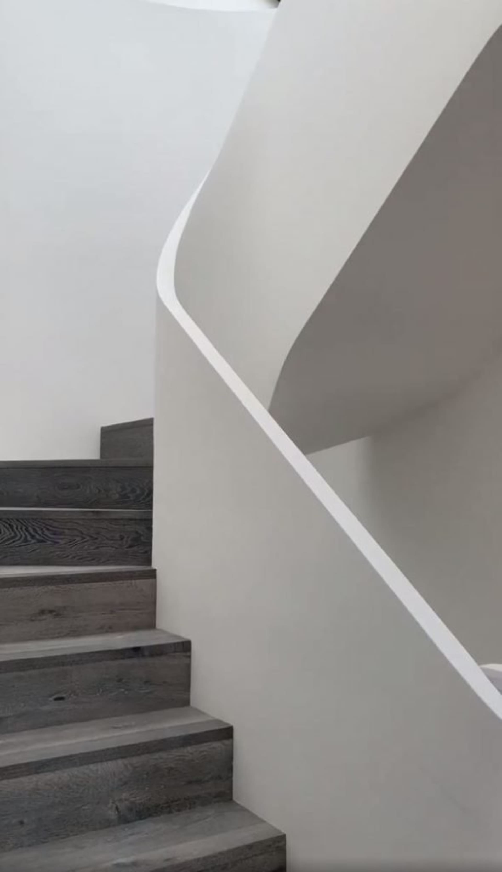 A modern staircase with wooden steps and a white rail.