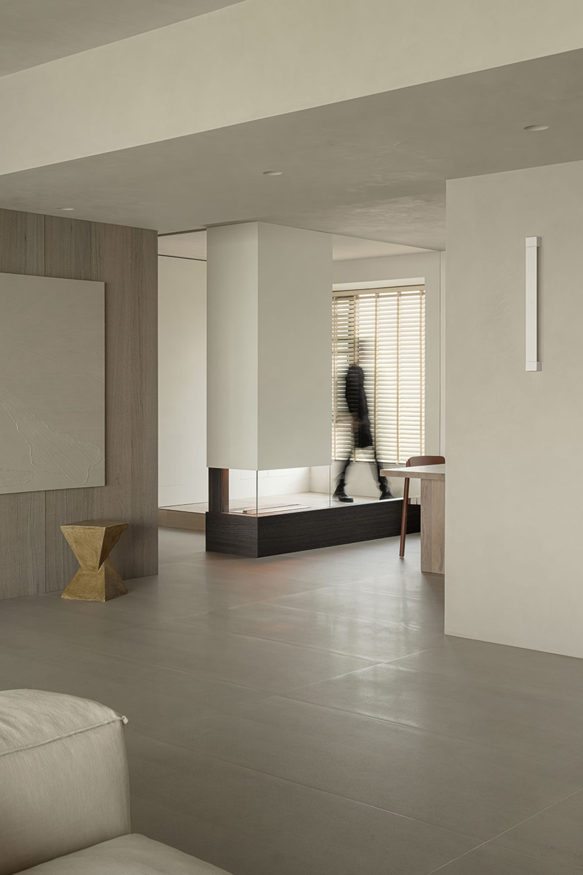 Modern minimalist living room with concrete flooring and wooden furniture, featuring clean lines and natural light.