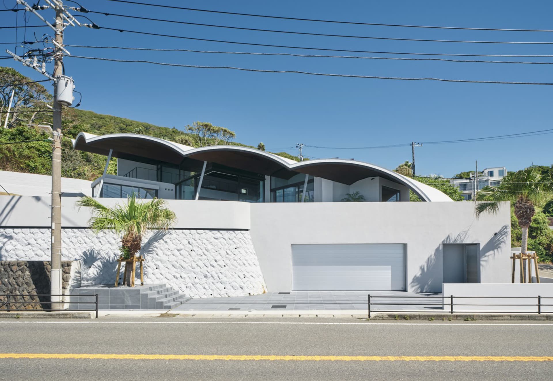 A modern residential exterior with curved concrete walls and a large glass window.