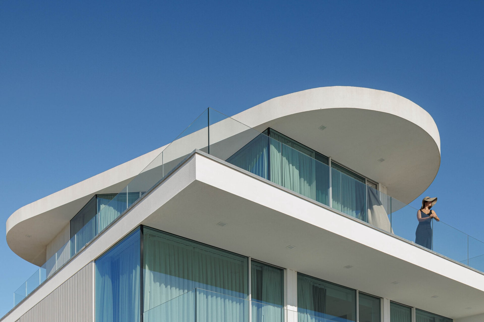 A modern house with a curved roof and glass walls.