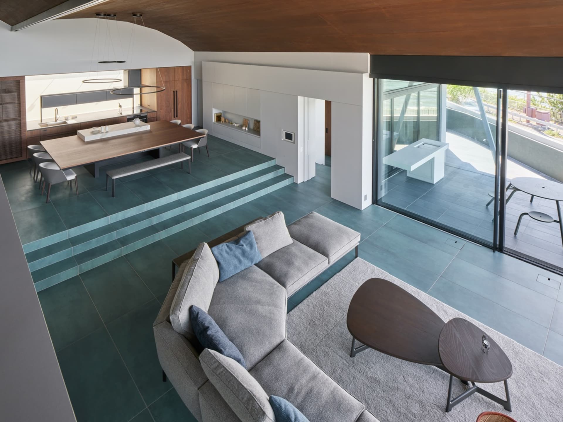 Minimalist living room with a concrete floor, a gray sectional sofa, and a wooden coffee table.