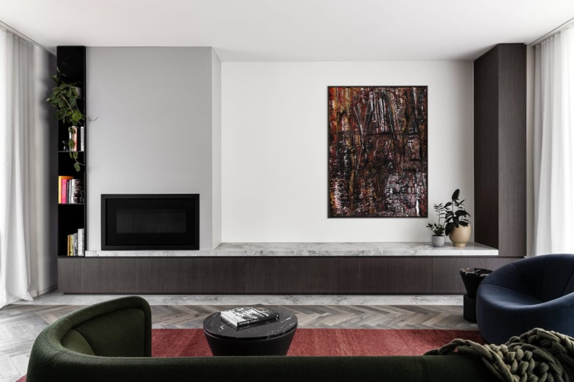 A modern living room featuring a marble fireplace, dark wood furniture, and abstract art. Dark and cozy with a contrast of te