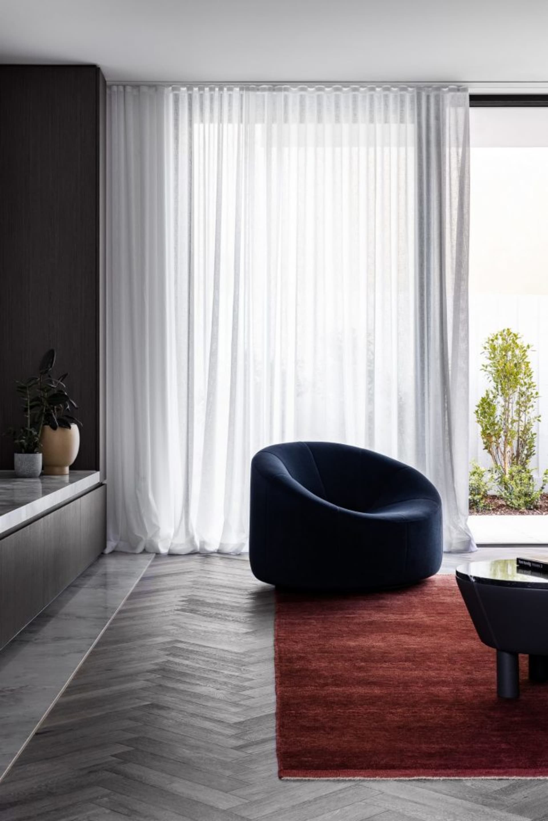 A modern living room featuring textured curtains, a marble floor, and wooden paneling.