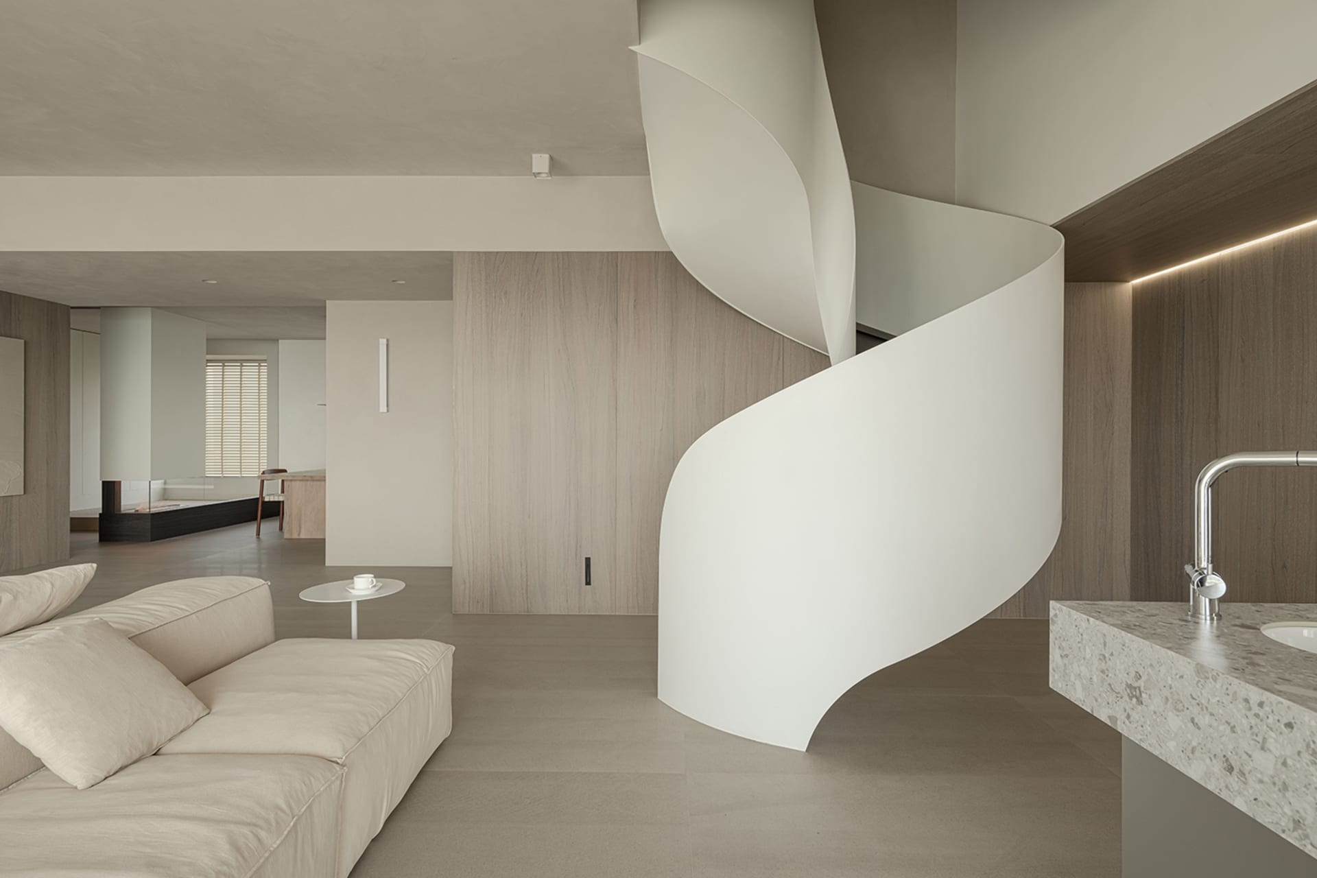 A modern living space featuring neutral-toned walls, flooring, and furniture.