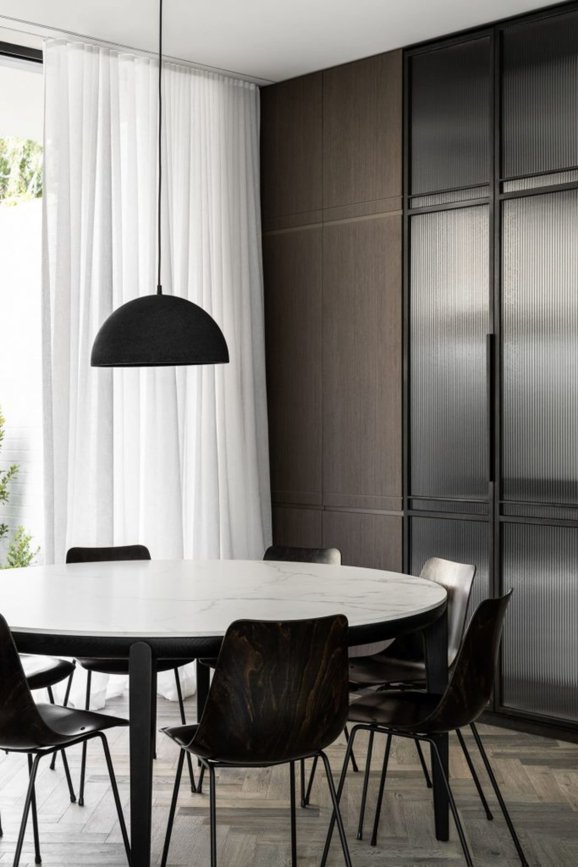 Modern minimalist dining room with marble table and dark wooden chairs