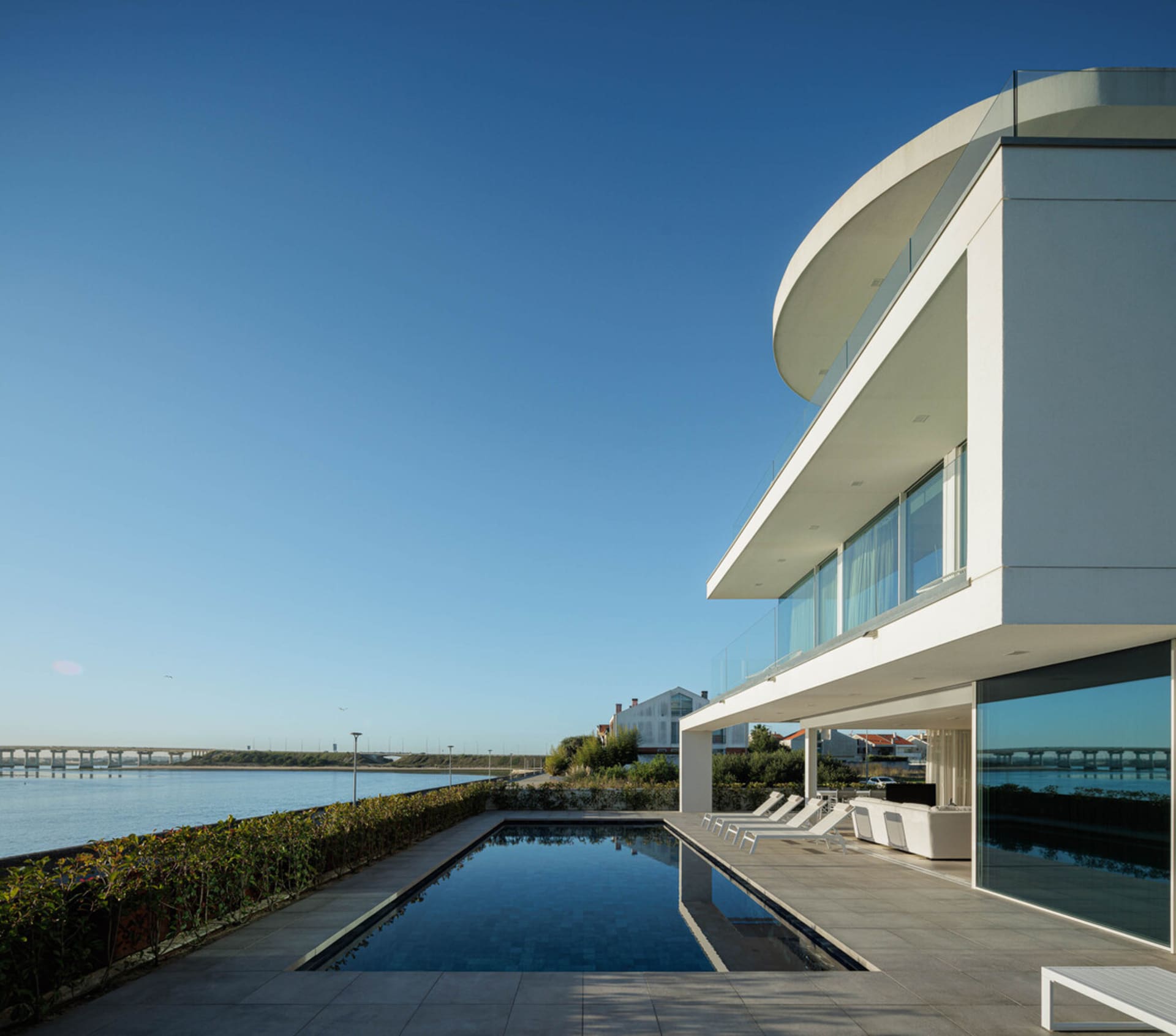 Modern house with a waterfront view featuring concrete and glass elements.