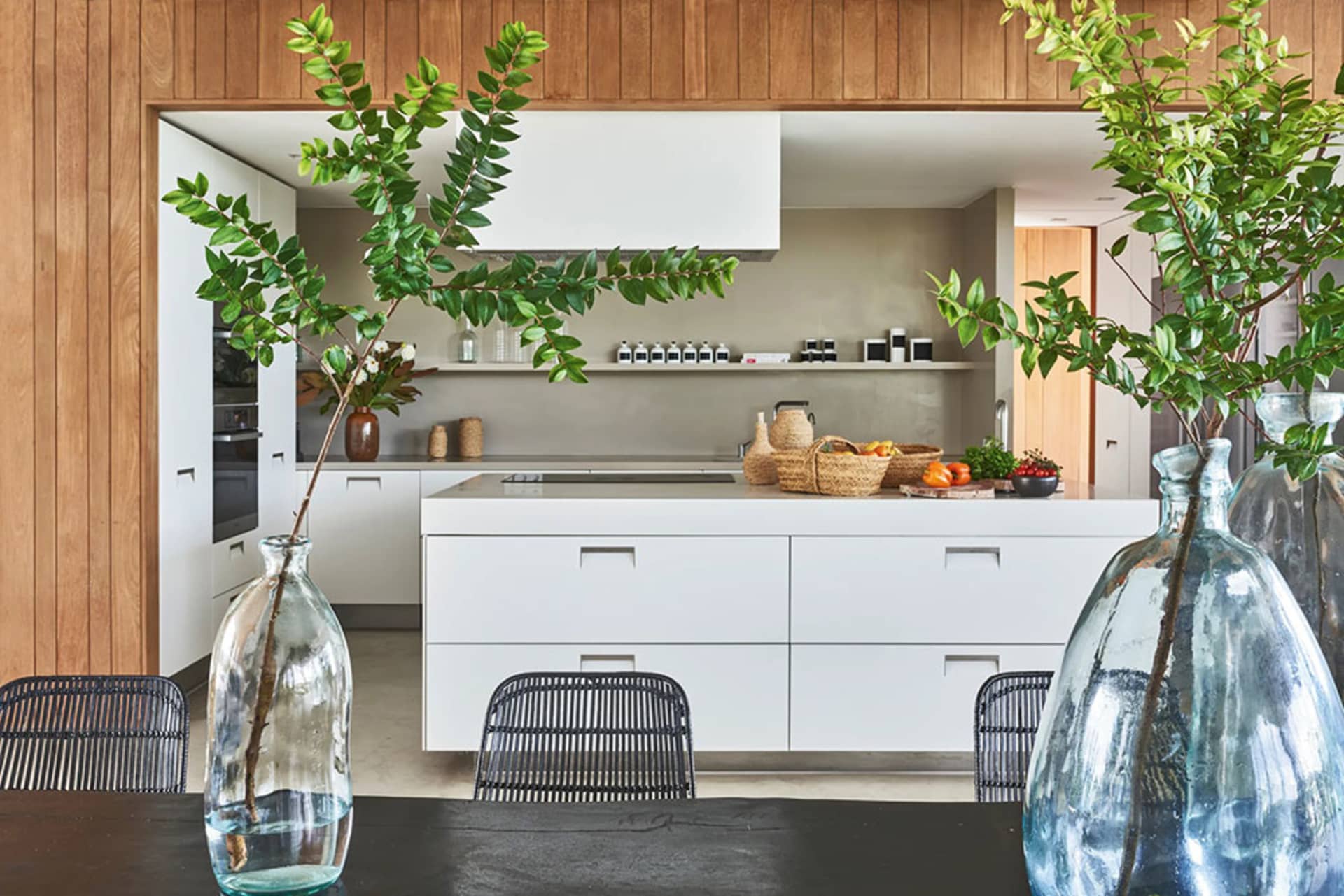 A modern kitchen features white cabinets, wooden countertops, and a central island equipped with a sink and various decorativ