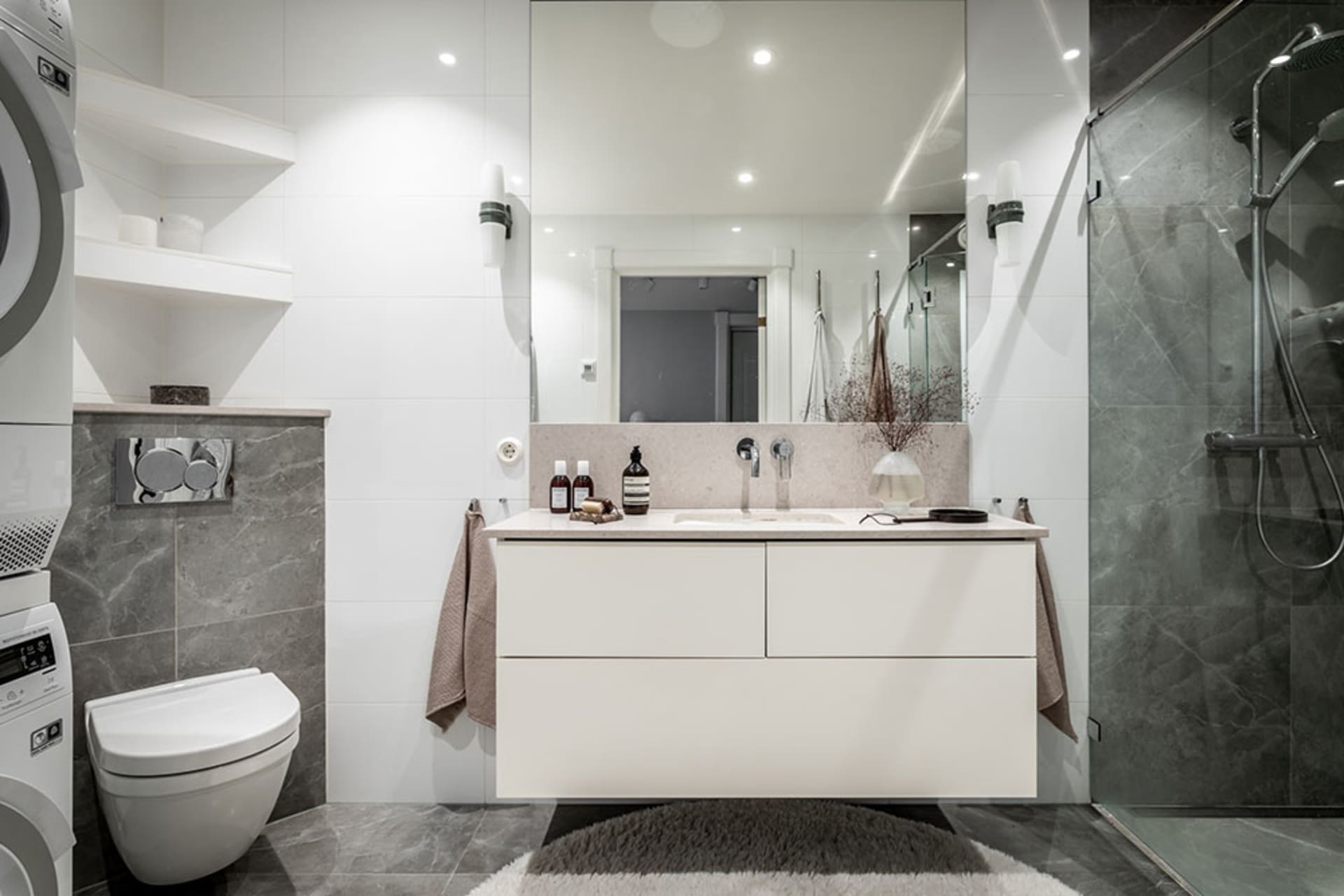 Modern minimalist bathroom with gray marble tiles, white fixtures, and floating vanity