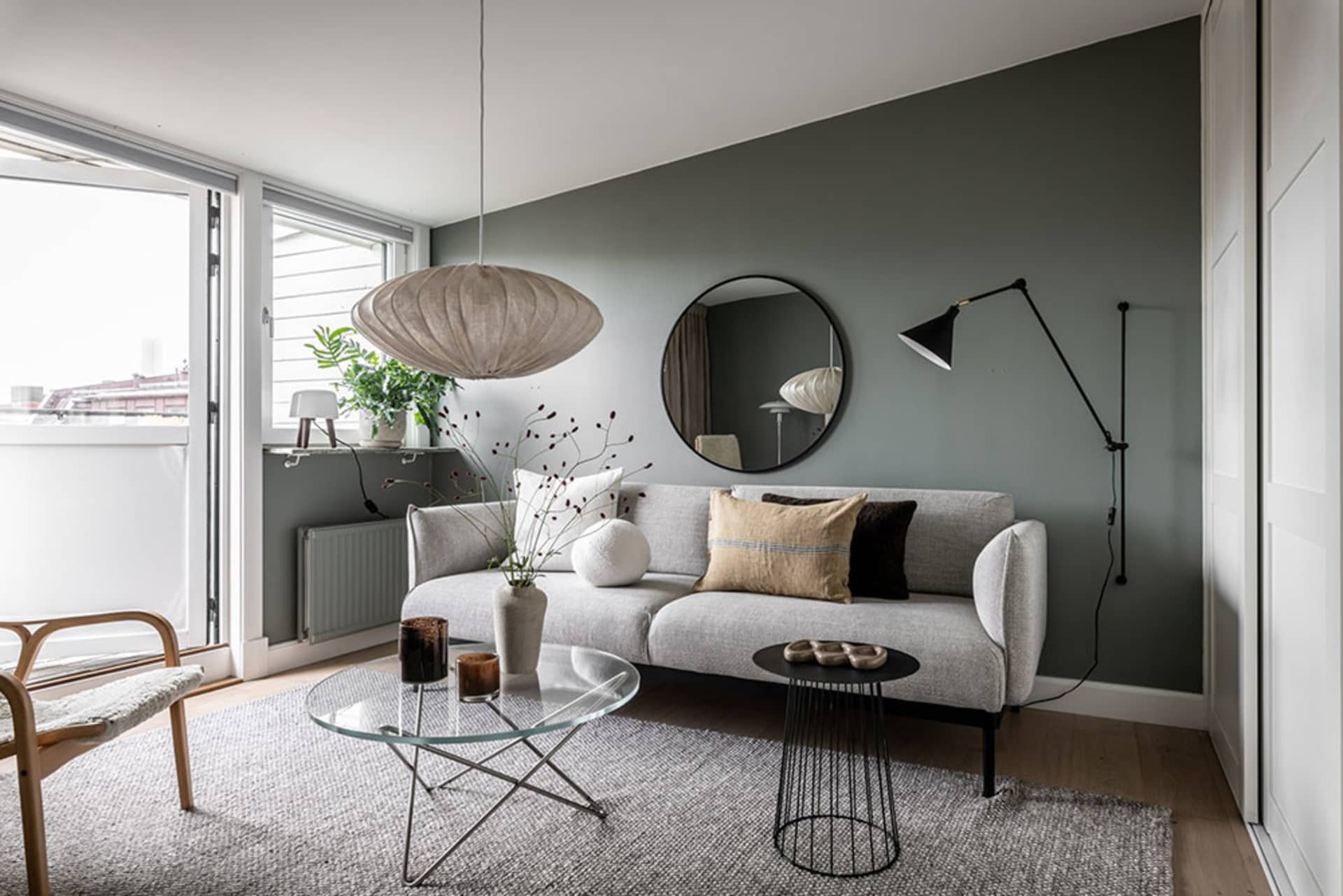 A modern minimalist living room with a grey couch, wooden floor, and metal coffee table.