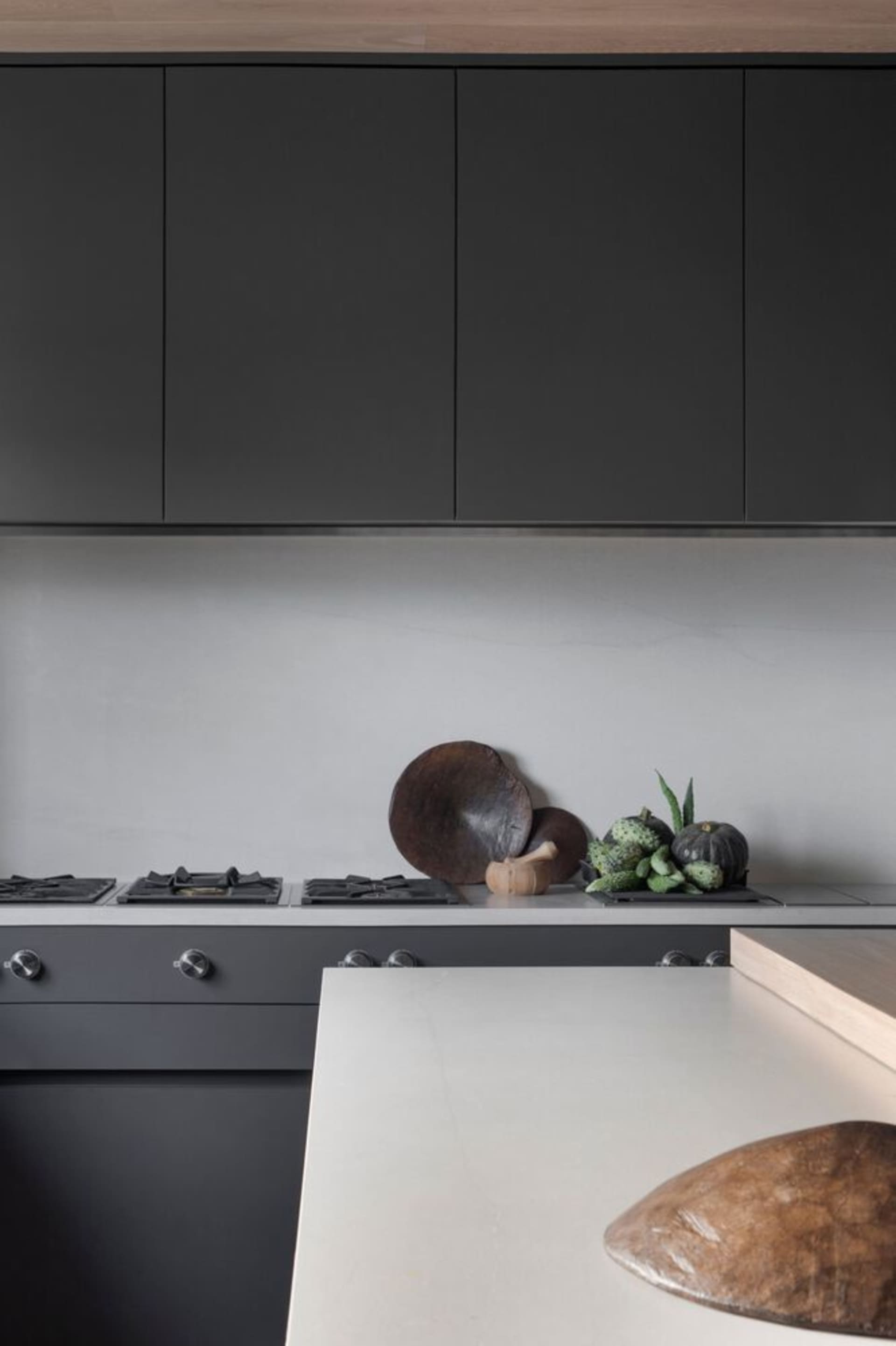 Modern kitchen with black cabinets and a natural stone countertop.