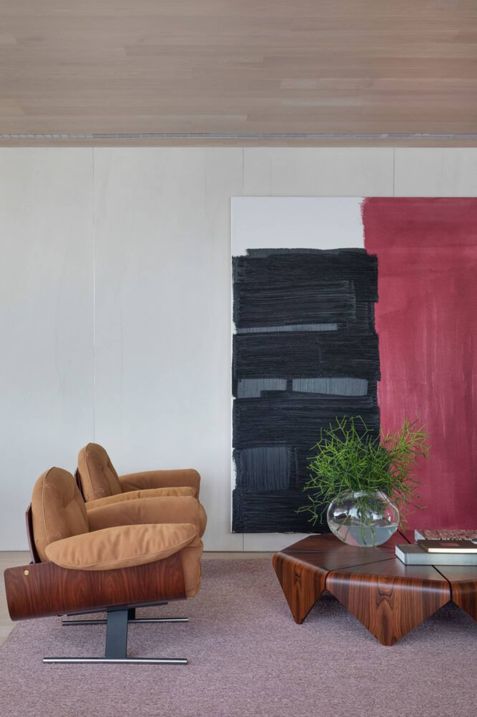 Modern living room with wooden furniture, abstract painting, and potted plant.
