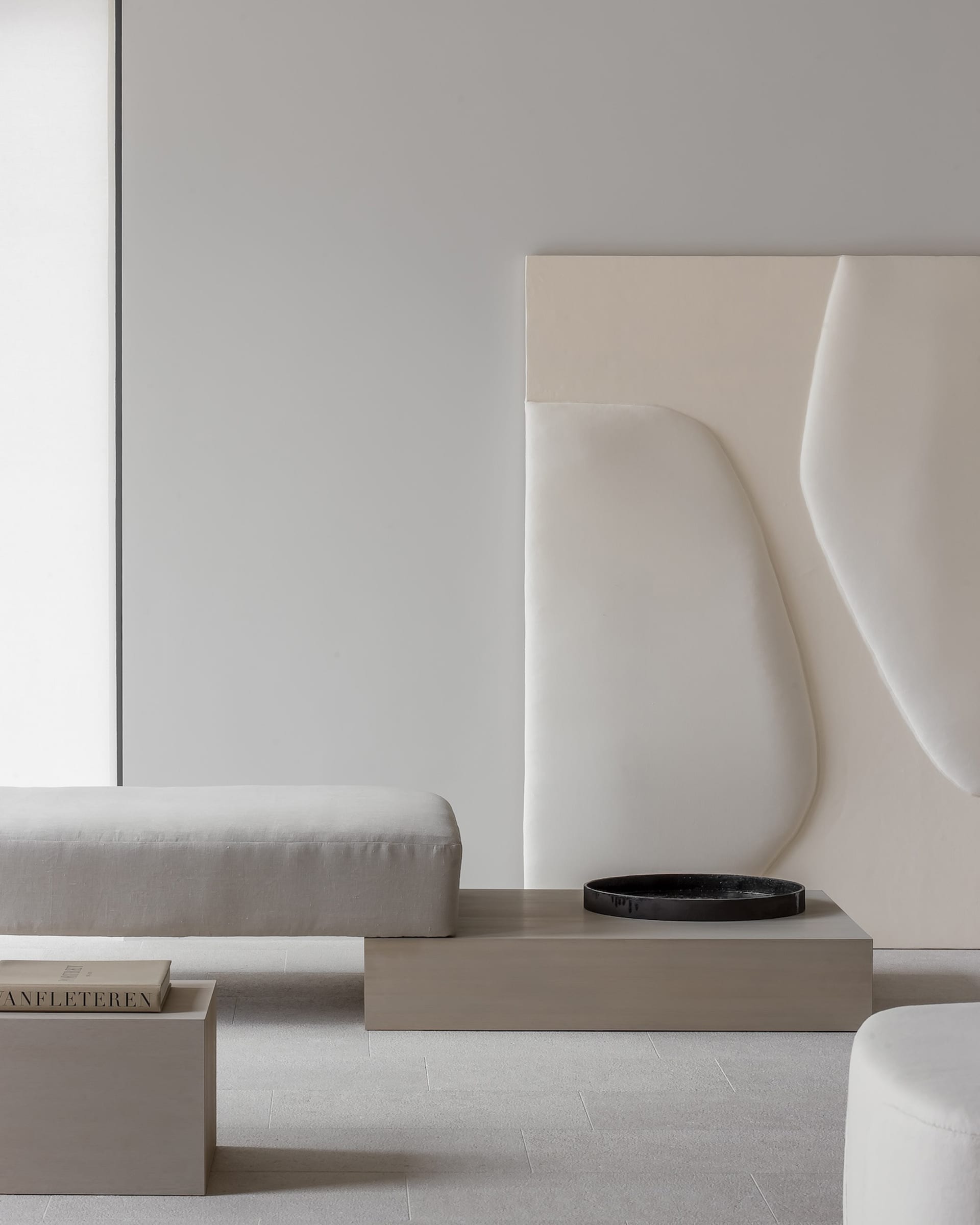 A minimalist living room with white-painted walls and concrete furniture.