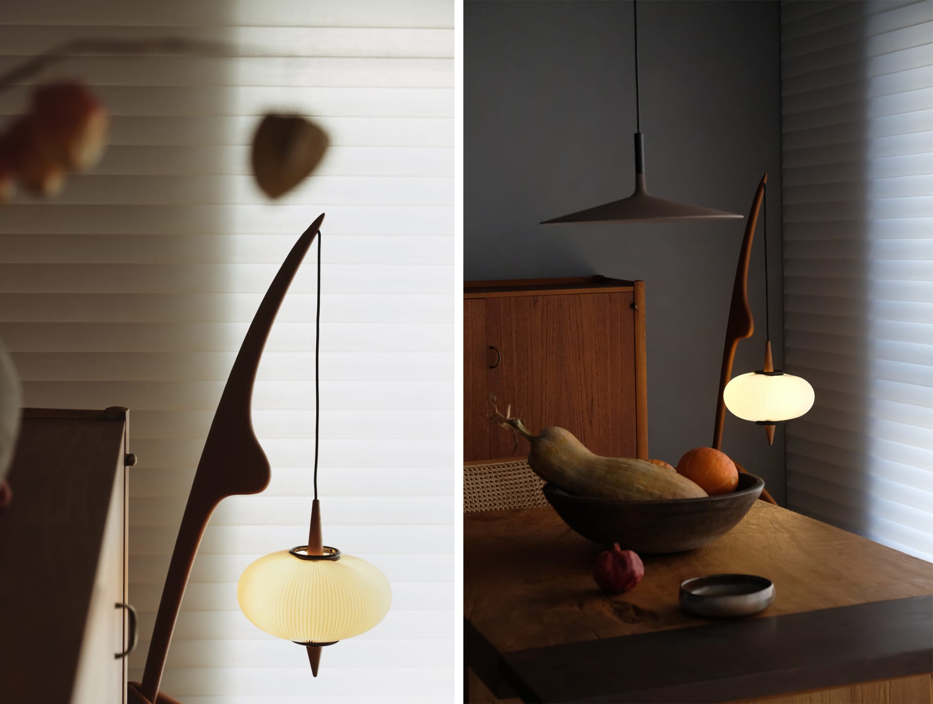 A modern kitchen interior featuring wooden furniture, glass pendant lights, and a bowl of fruits.
