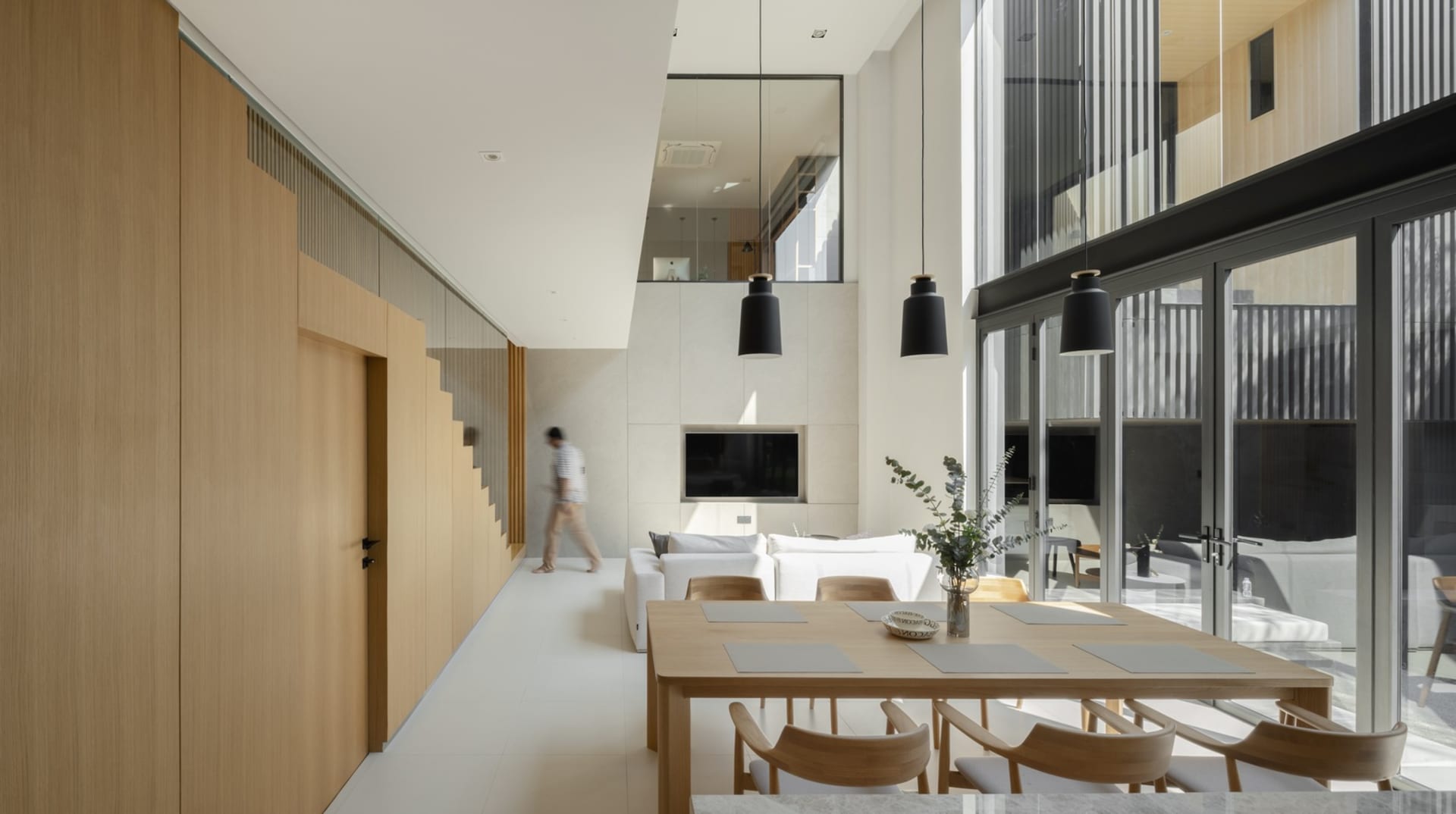 Modern living and dining space featuring a minimalist interior design with concrete and glass elements.