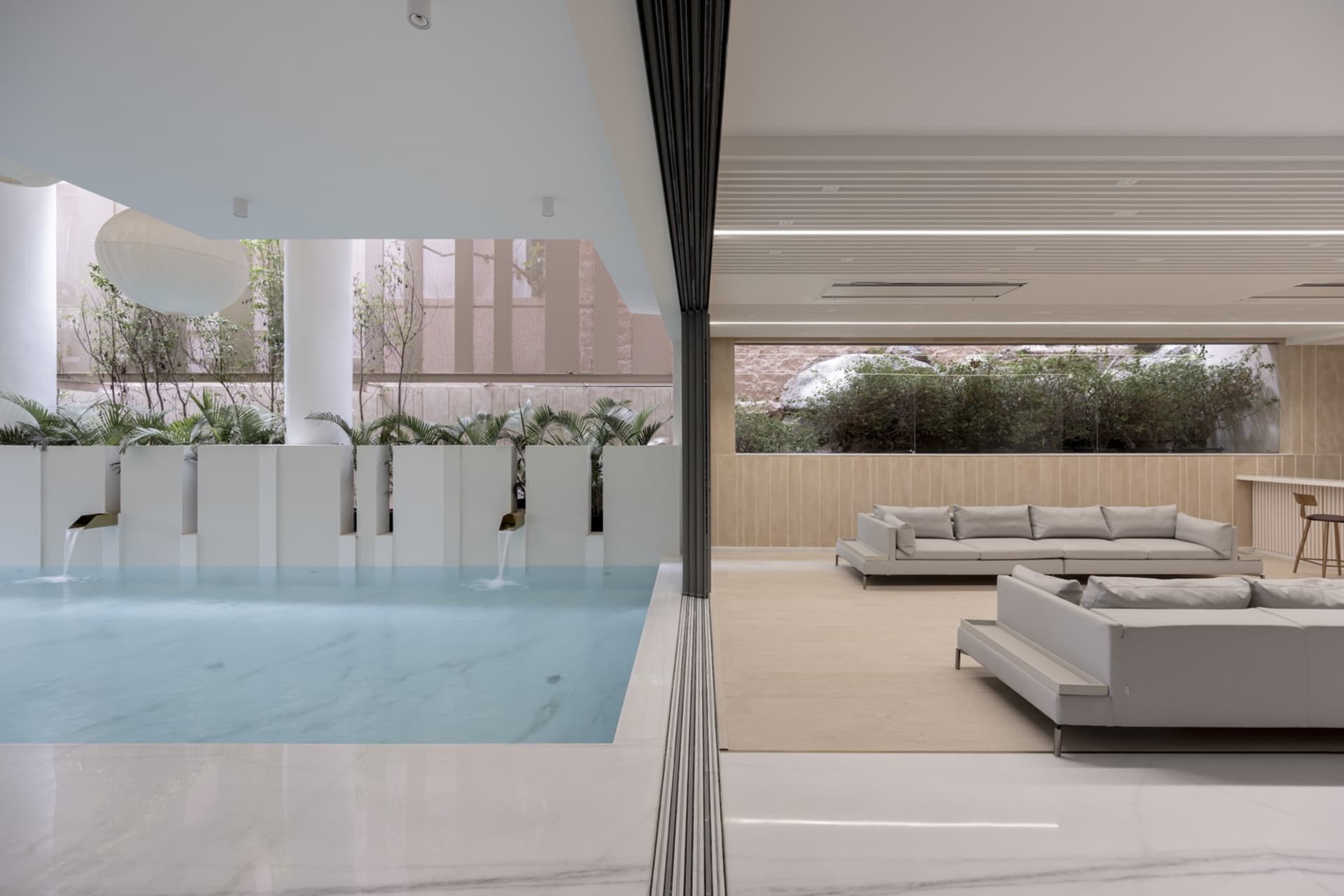 Modern minimalist living room with concrete walls, glass windows, and marble furniture.