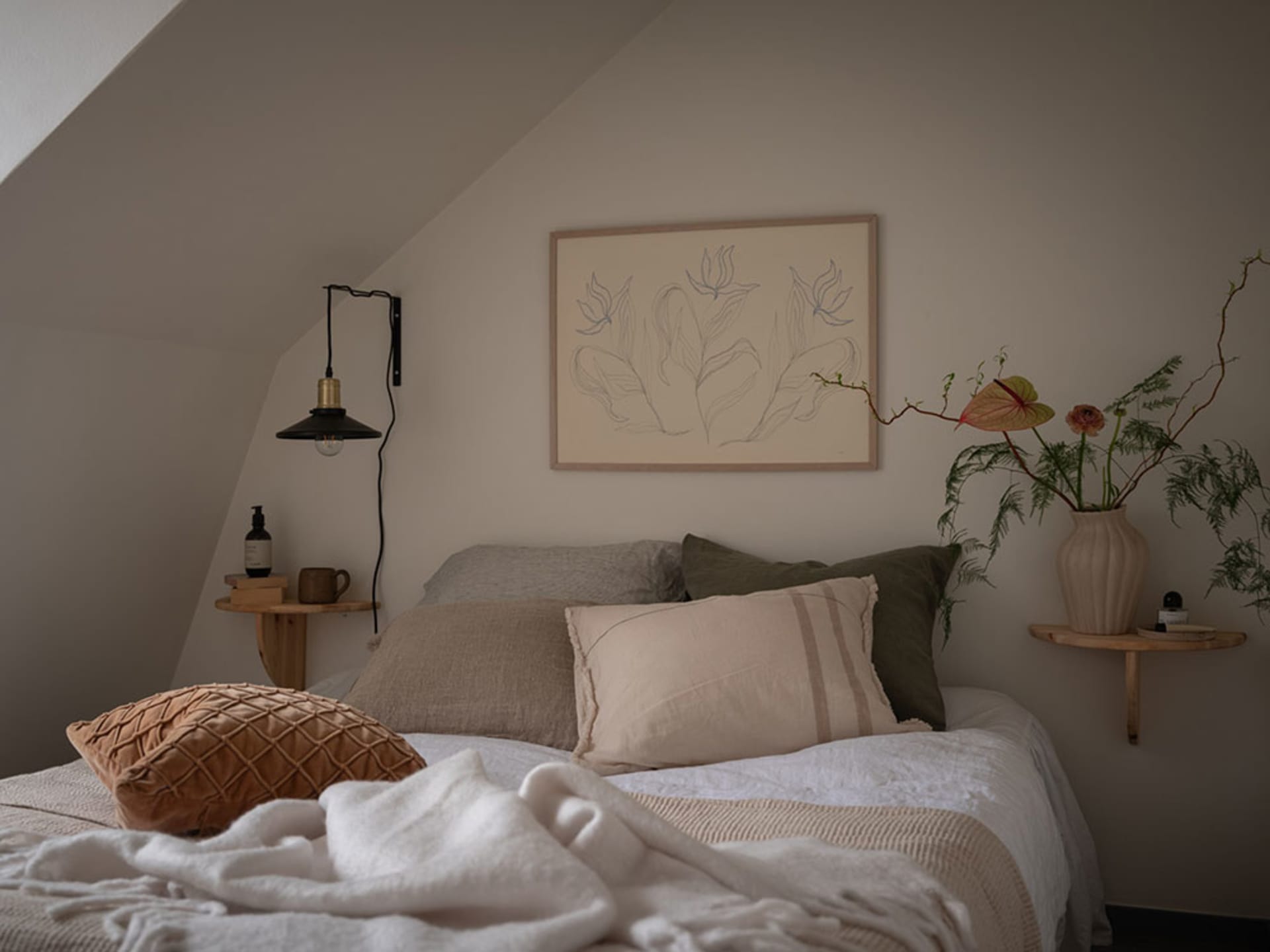 A neatly made bed with a minimalist design, featuring fabric bedding and a wooden frame, surrounded by natural light and simp