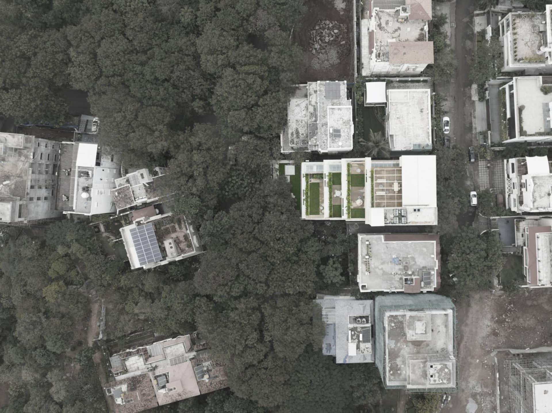 Aerial view of modern housing development with concrete roofs and surrounding greenery.