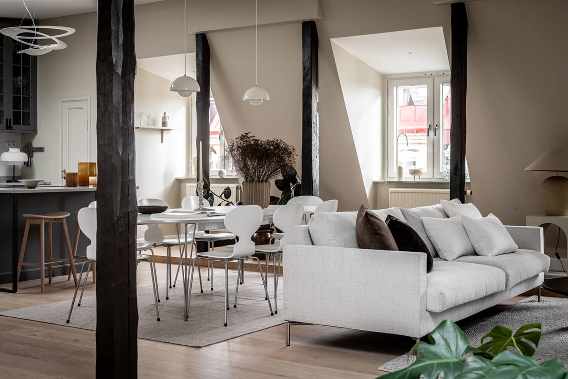 A modern living room with a white sofa, wooden flooring, and a table with chairs.