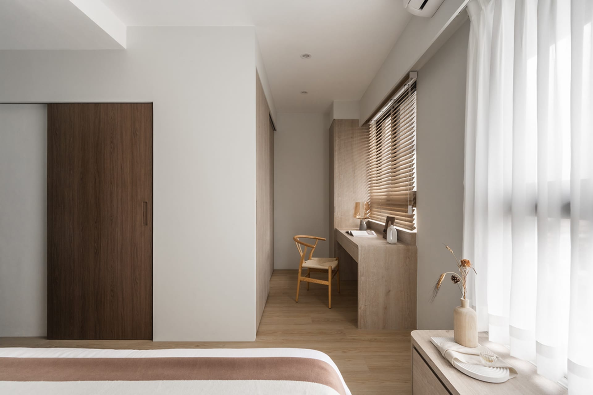 A minimalist bedroom featuring wooden furniture and materials, with soft lighting and a clean, uncluttered design.
