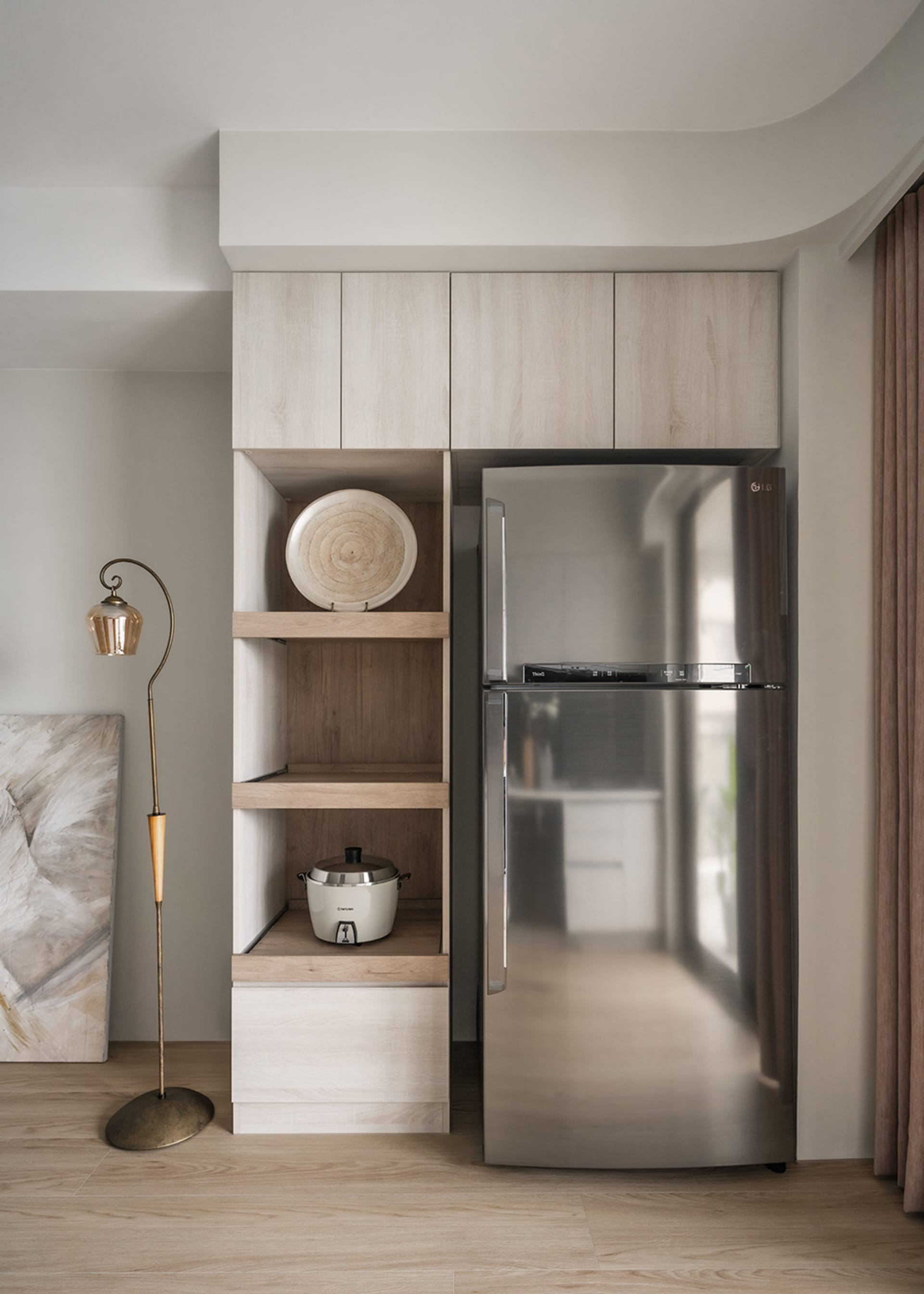 A minimalist kitchen featuring wooden shelves and a stainless steel refrigerator.