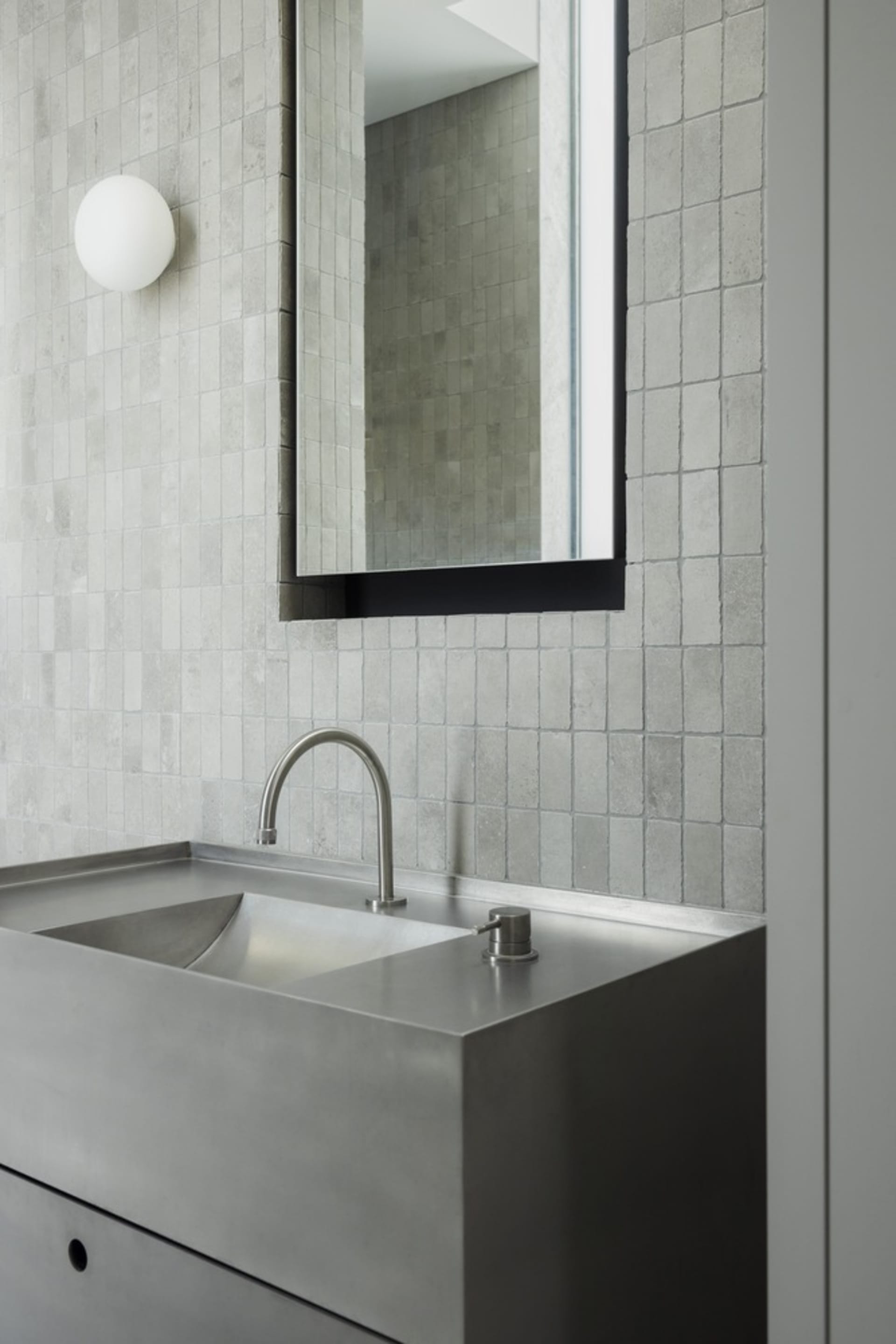 A modern minimalist bathroom with metallic sink and square tiles.