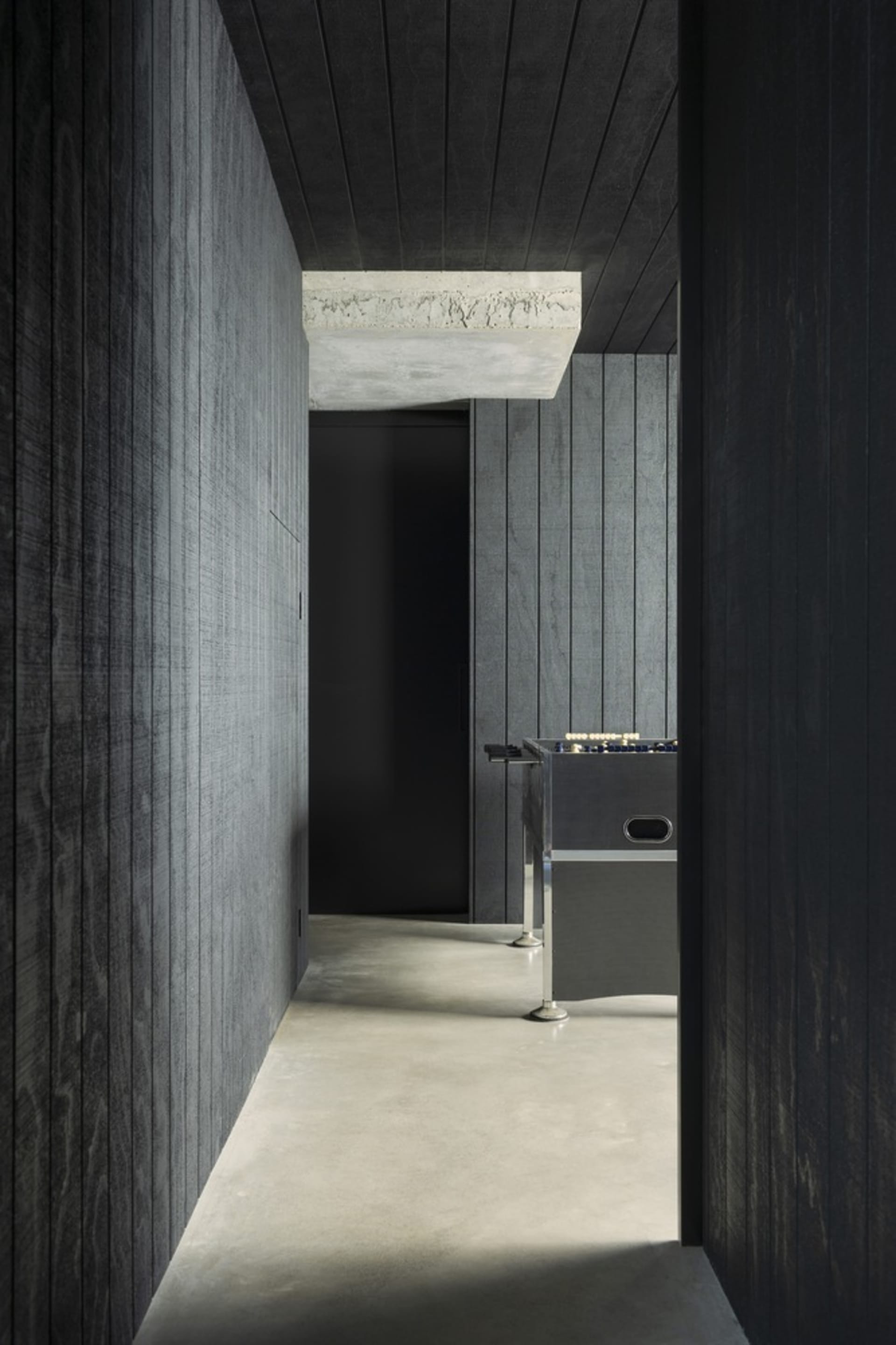A modern game room with concrete floors, walls, and ceiling.