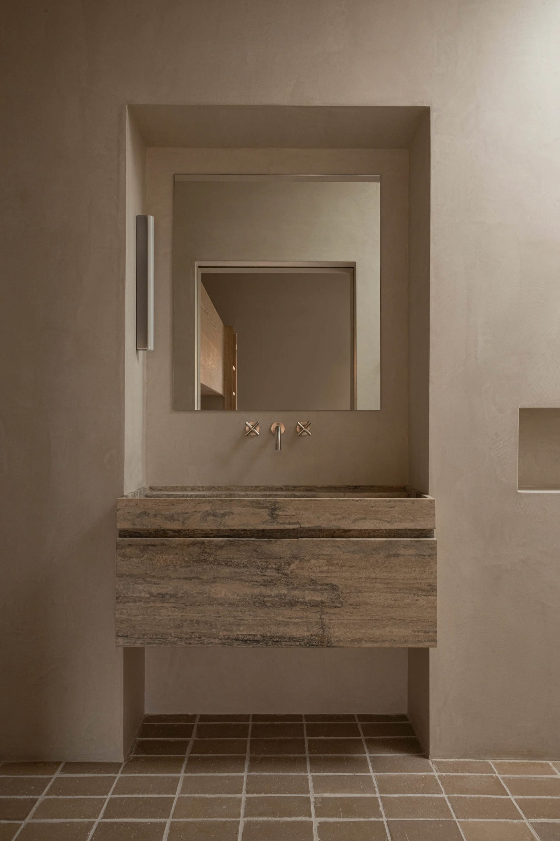 Modern minimalist bathroom with concrete walls and floor, featuring a floating vanity sink with a matching minimalist faucet
