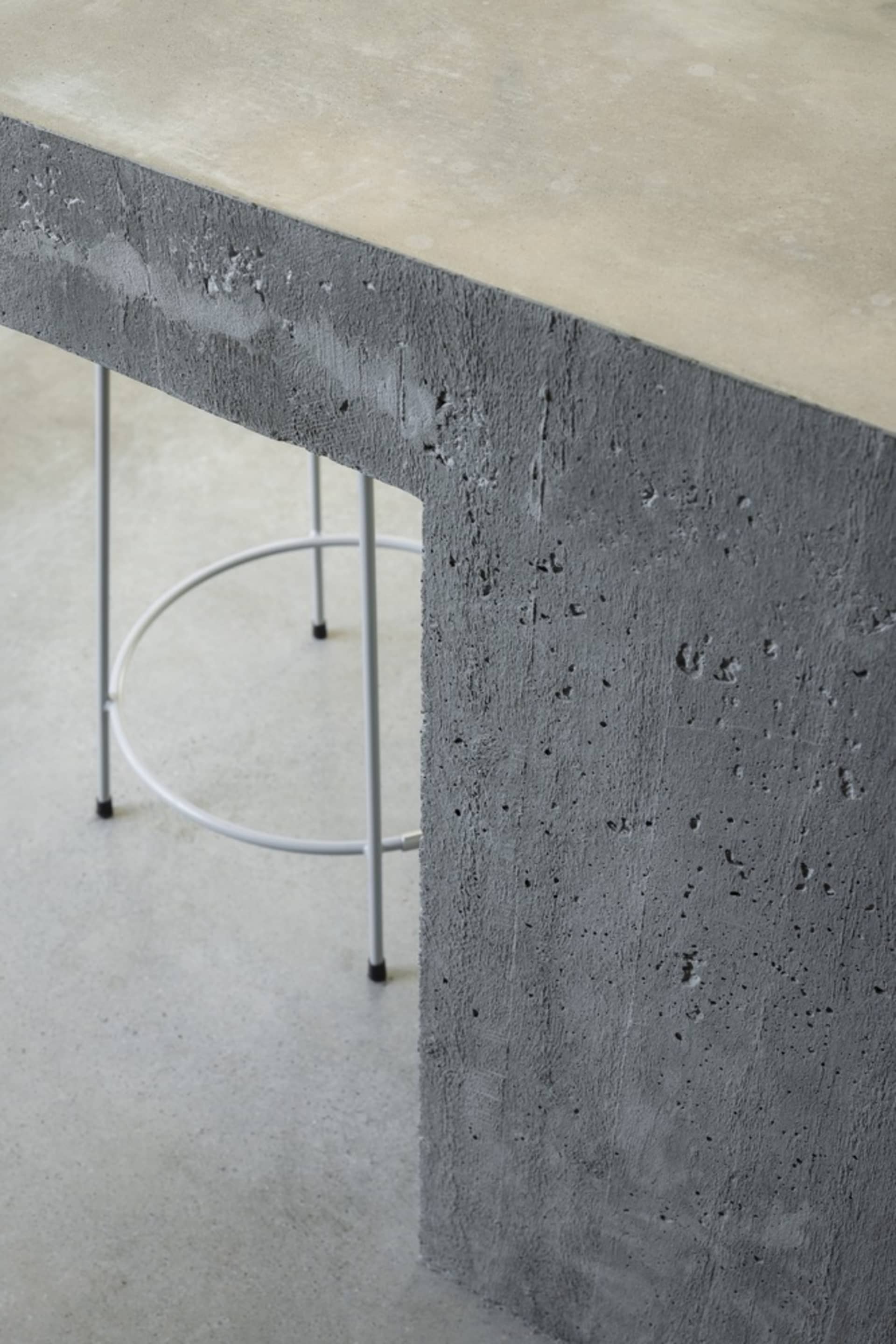 A sturdy, industrial-style concrete table with a minimalist white metal base.