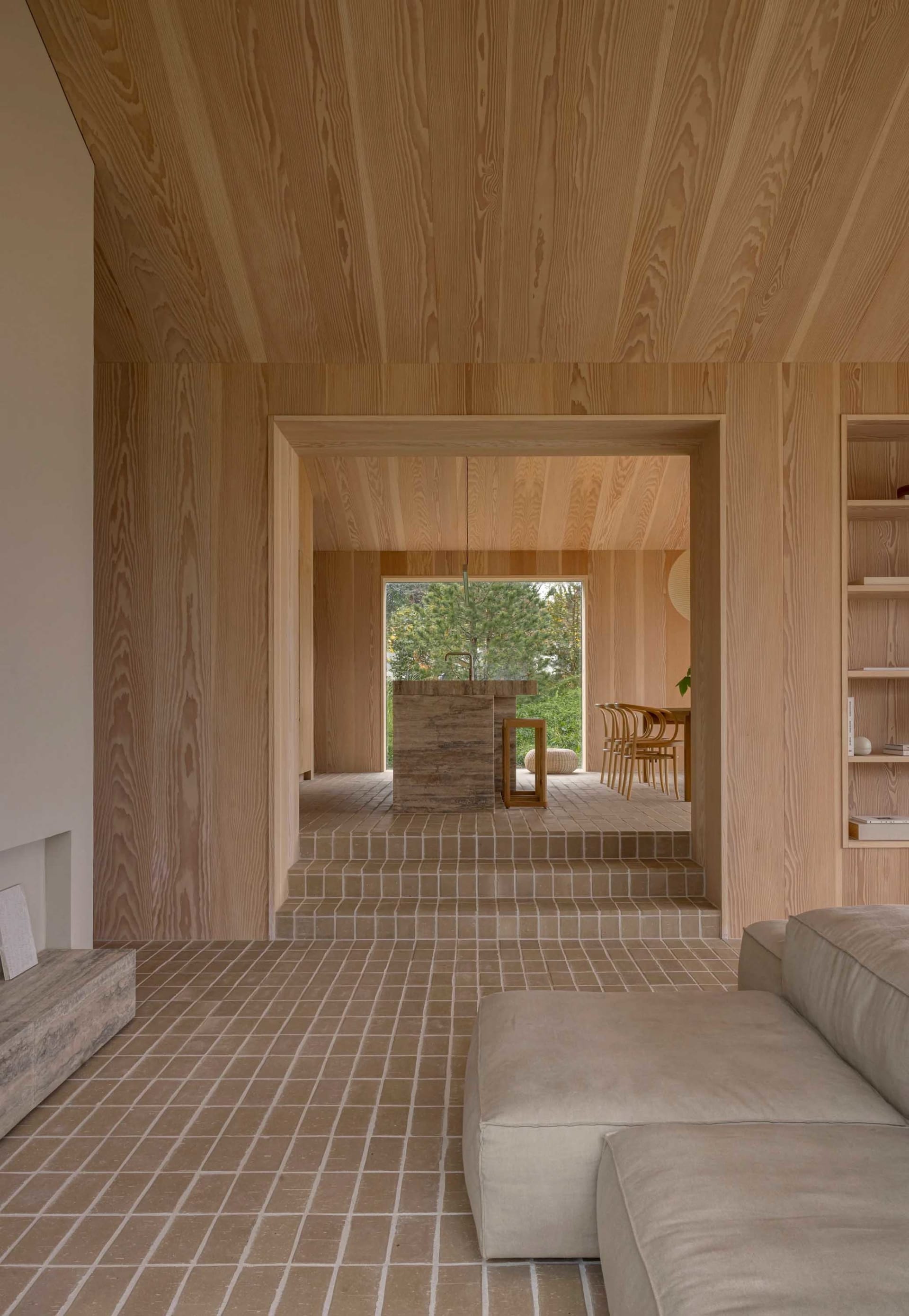 Interior of a minimalist living room with natural wood textures and a terrazzo floor.