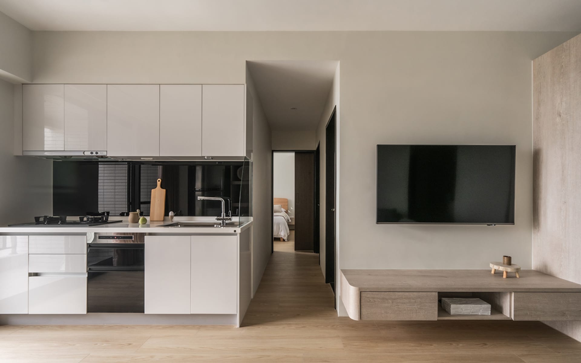 Modern residential kitchen with white lacquer cabinets, black countertops, and stainless steel appliances.